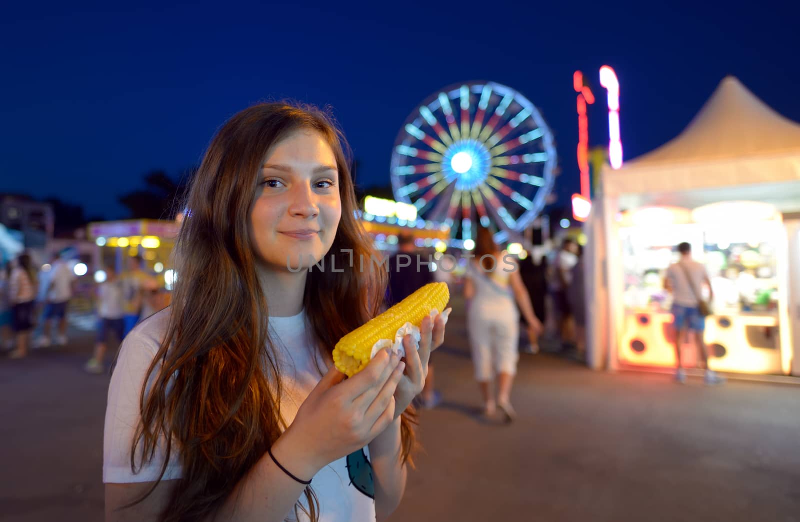 teen girl eating corn in fair
