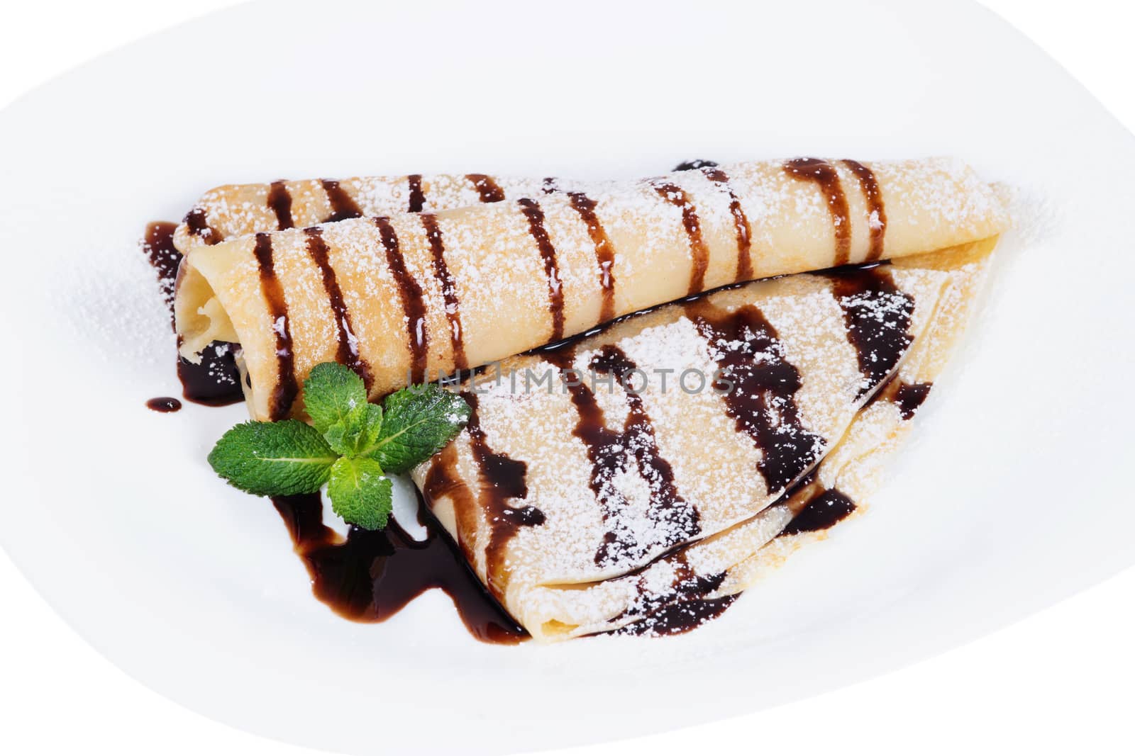 Pancakes with chocolate sauce and mint  on a plate, isolated