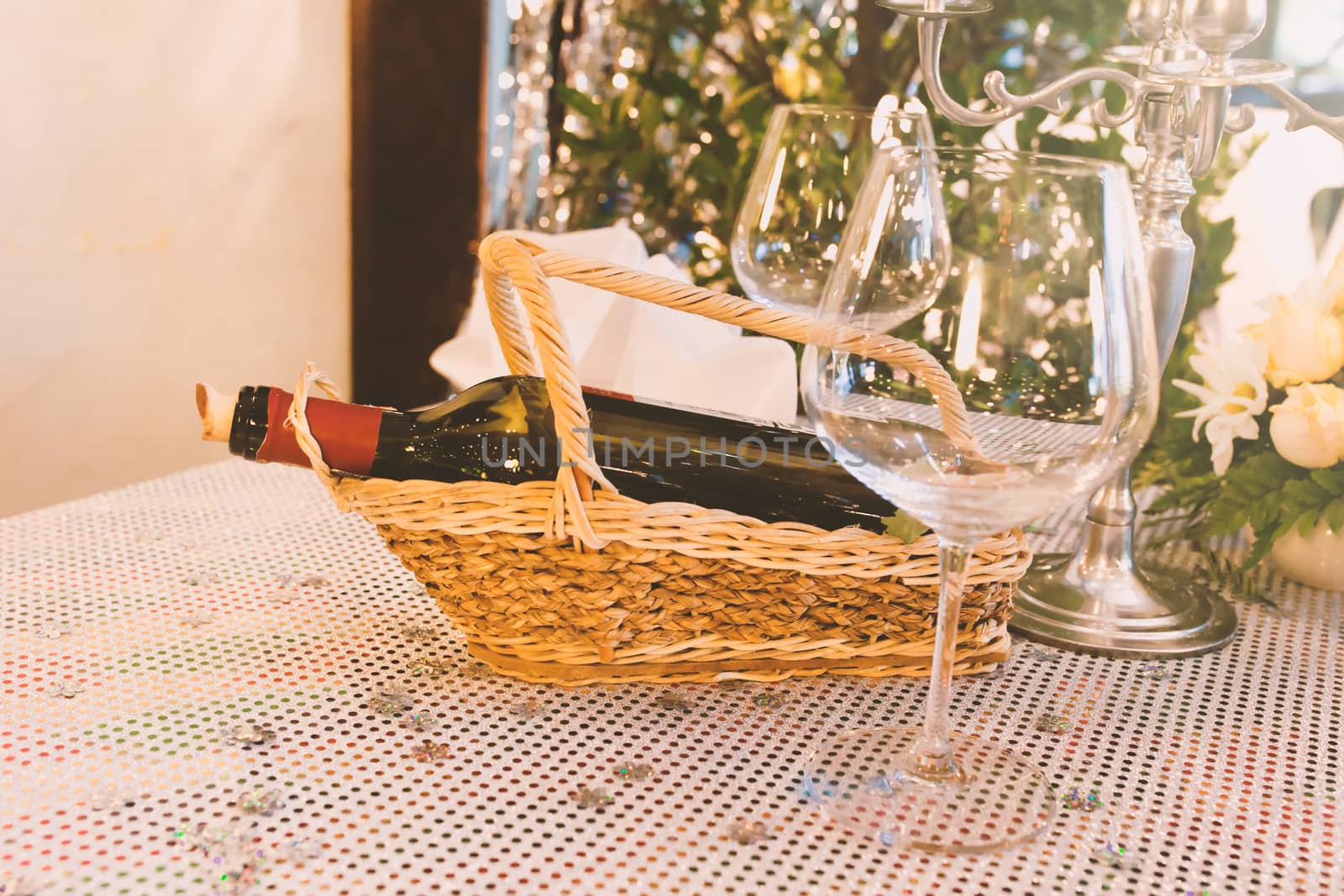 Bottle of wine on wood basket and Glasses on table.