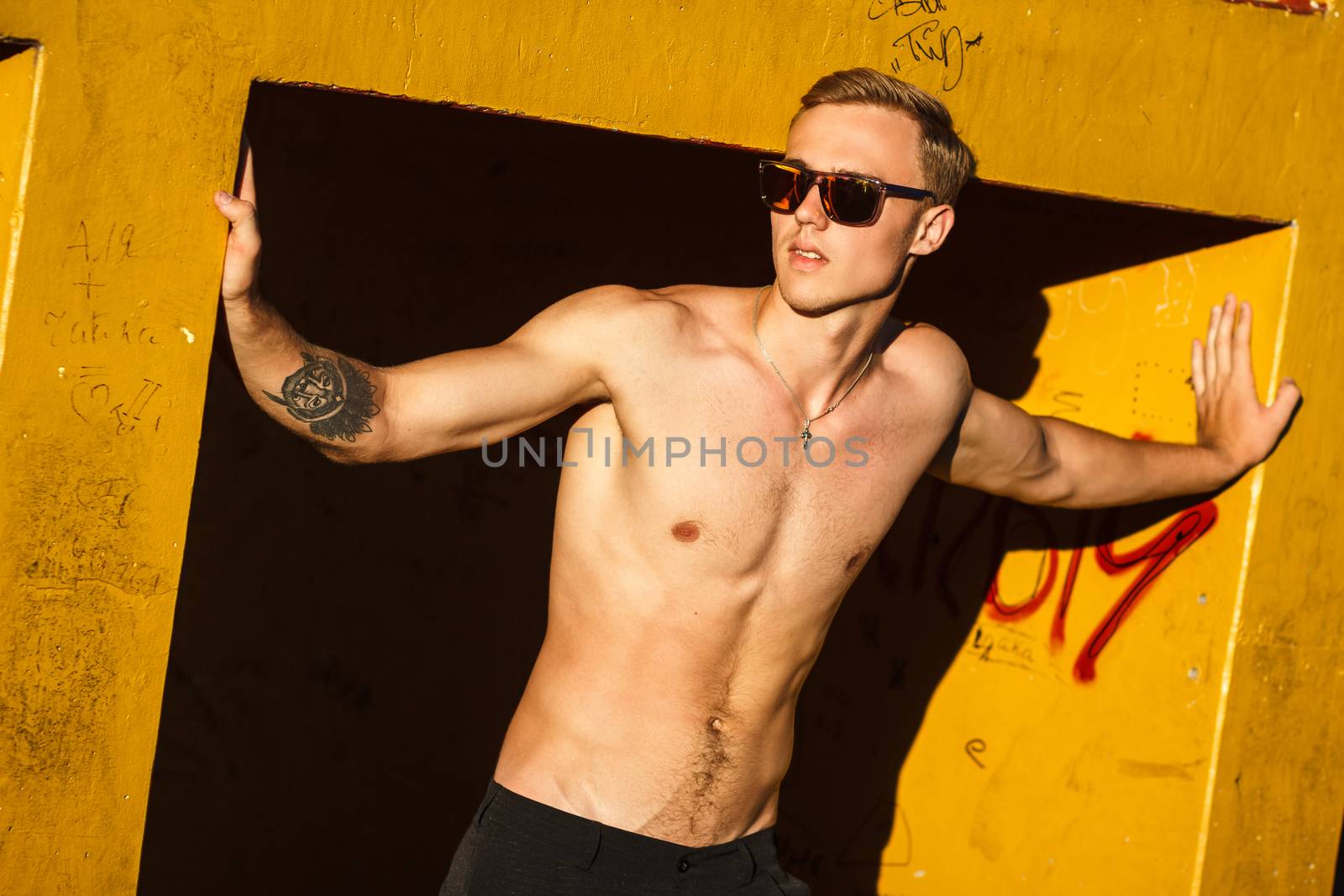 Young fit shirtless man exercising on outdoor sports ground. Concept: healthy lifestyle