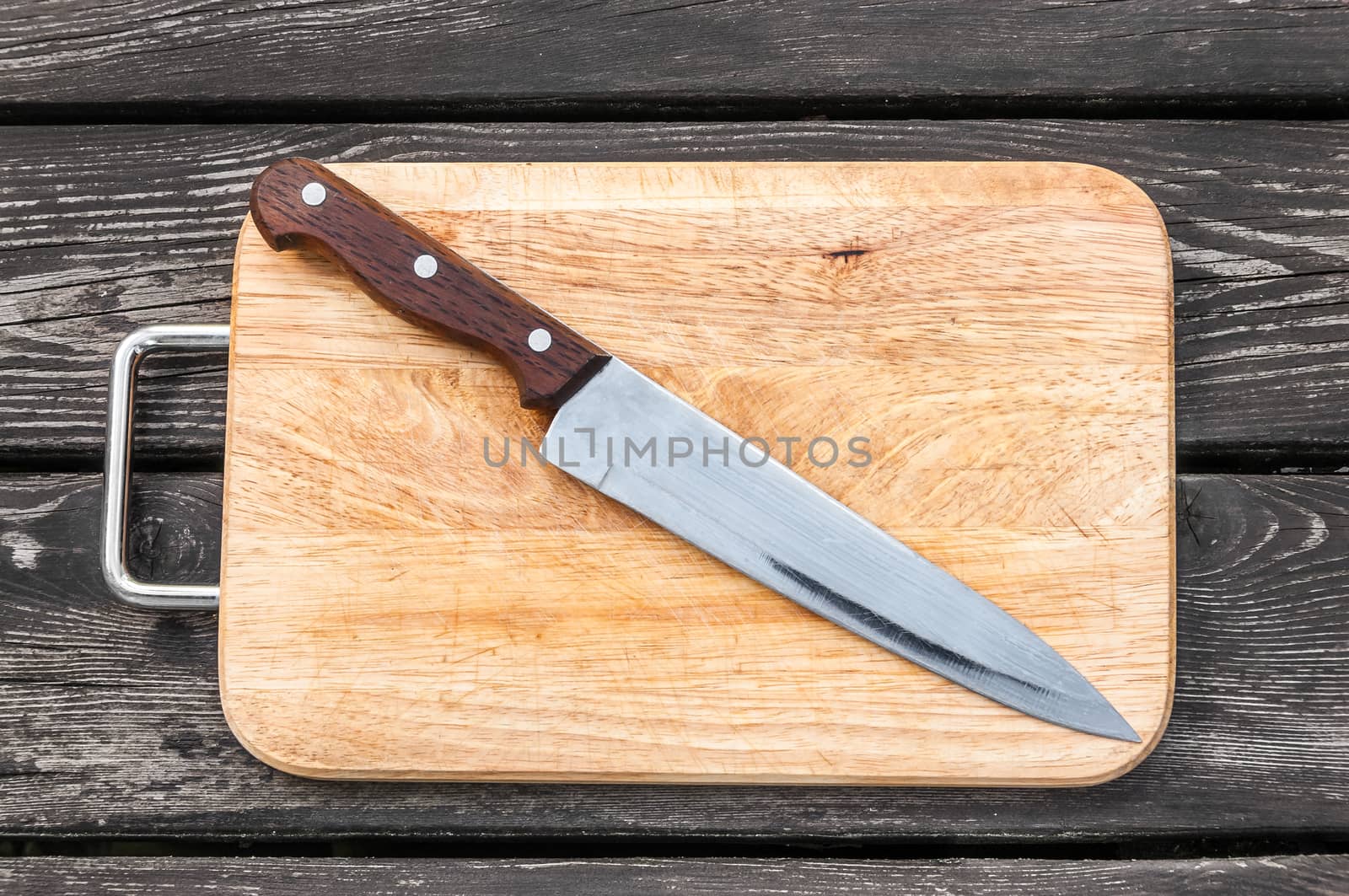 Steel knife on a cutting board on wooden background with 