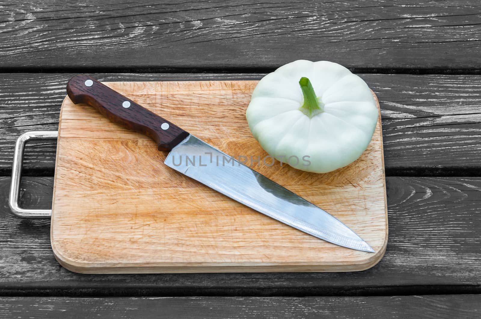 Squash on a cutting board on wooden background with a steel knife