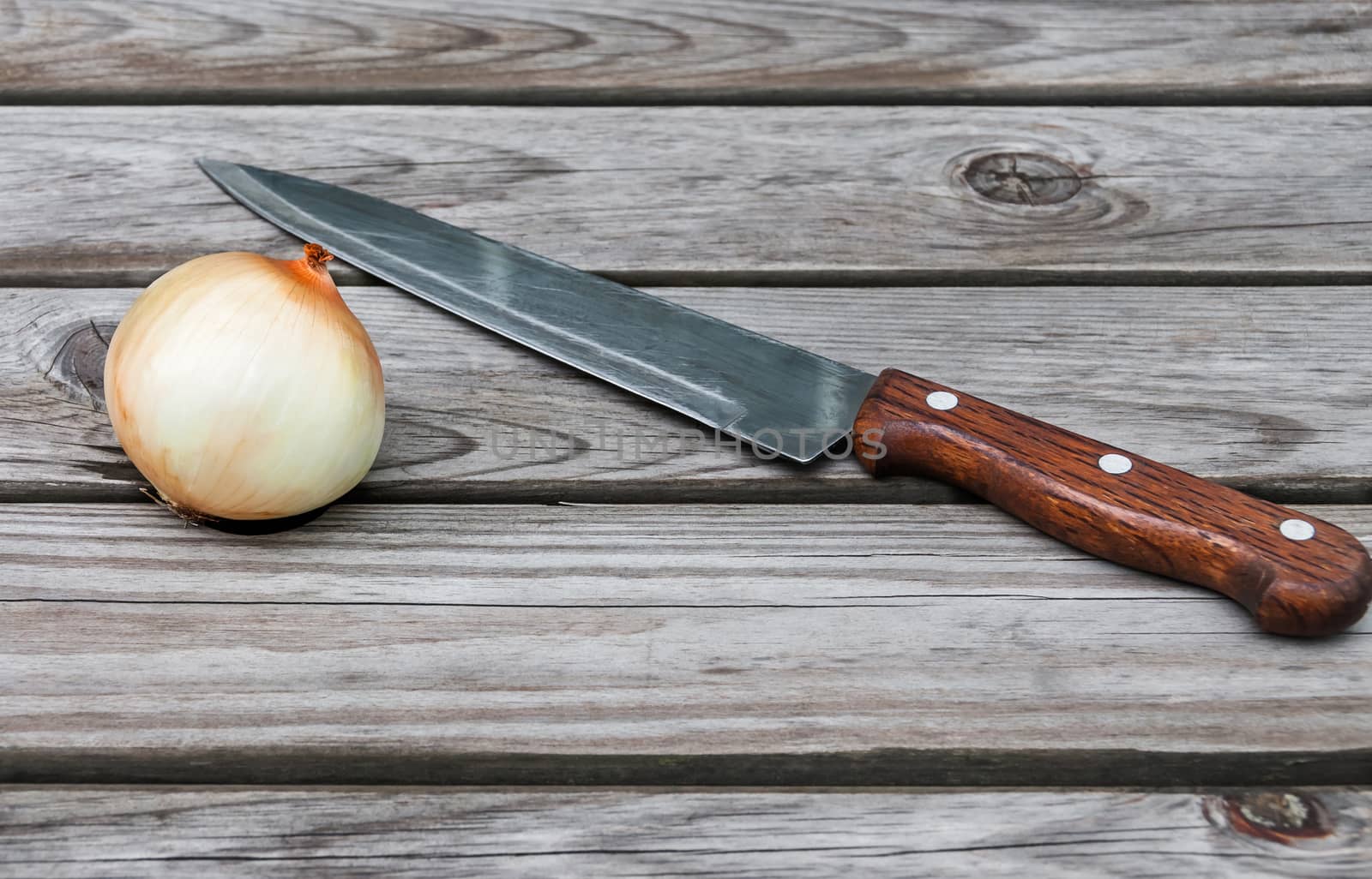 Knife,onion  on a table made of wooden planks