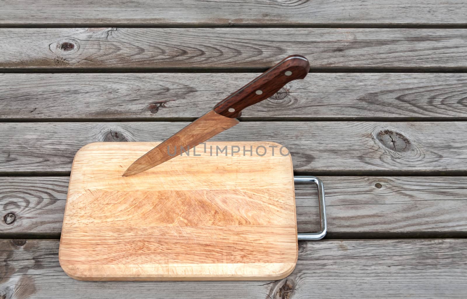 Steel knife and cutting board on a wooden table
