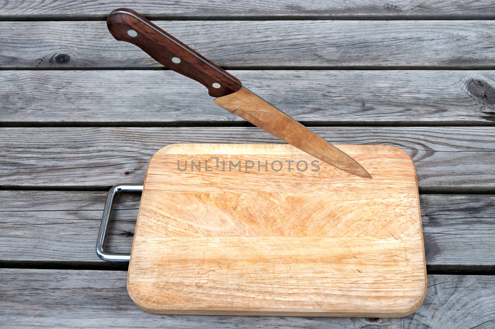 Steel knife and cutting board on a wooden table