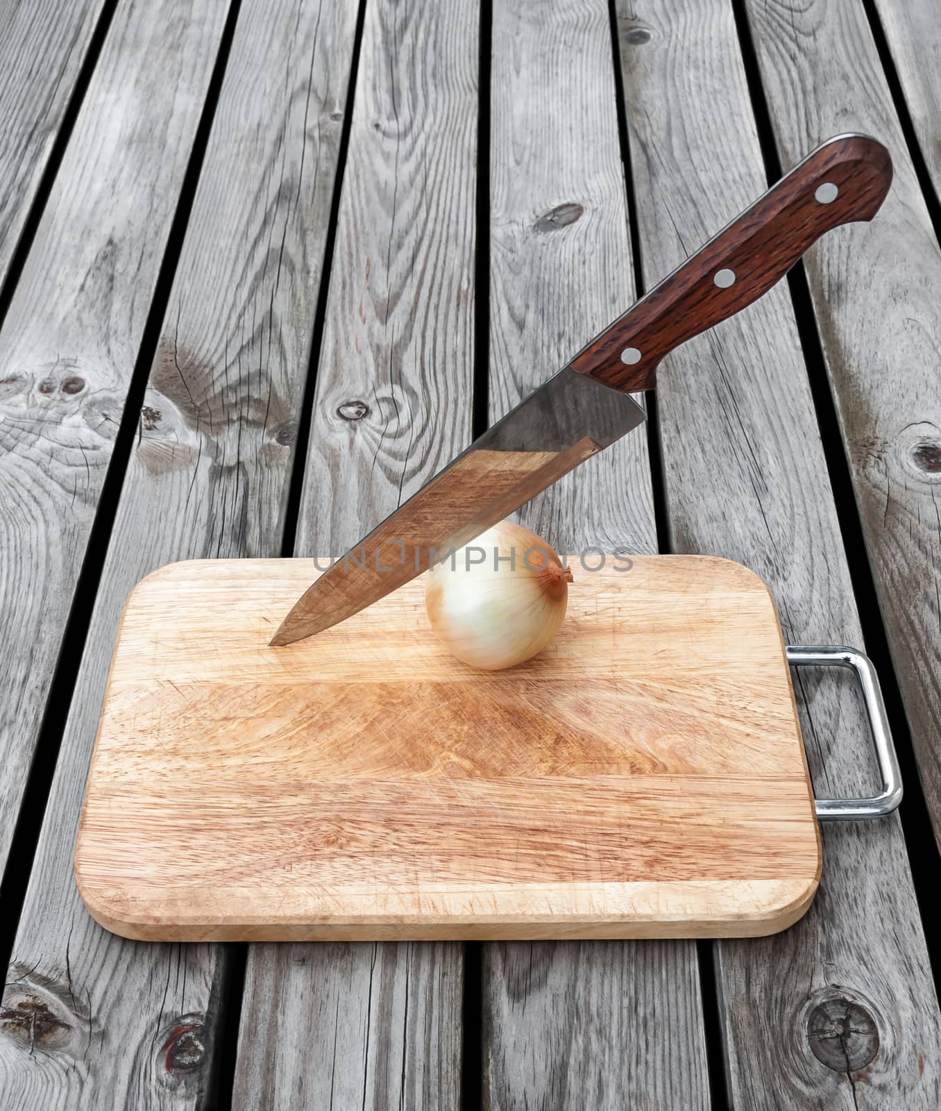 Knife,onion and a cutting board  on a wooden table