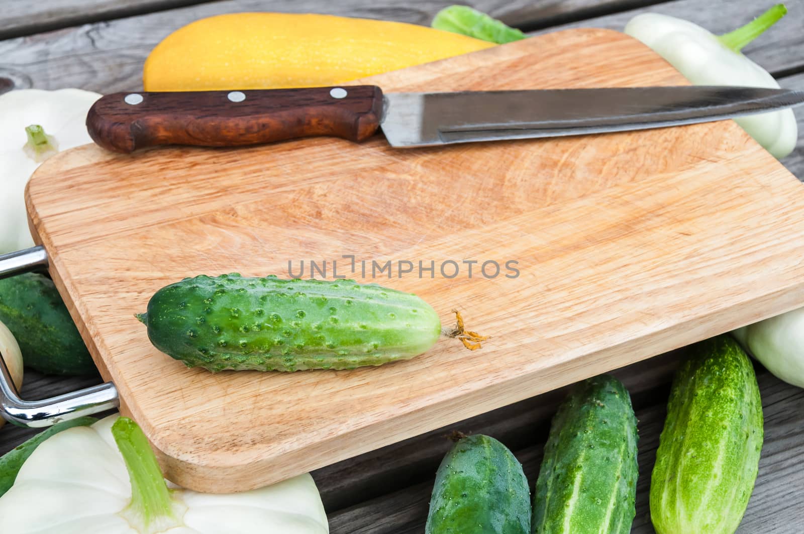 Cutting board, knife, fresh vegetables on wooden table.  Top view with copy space.