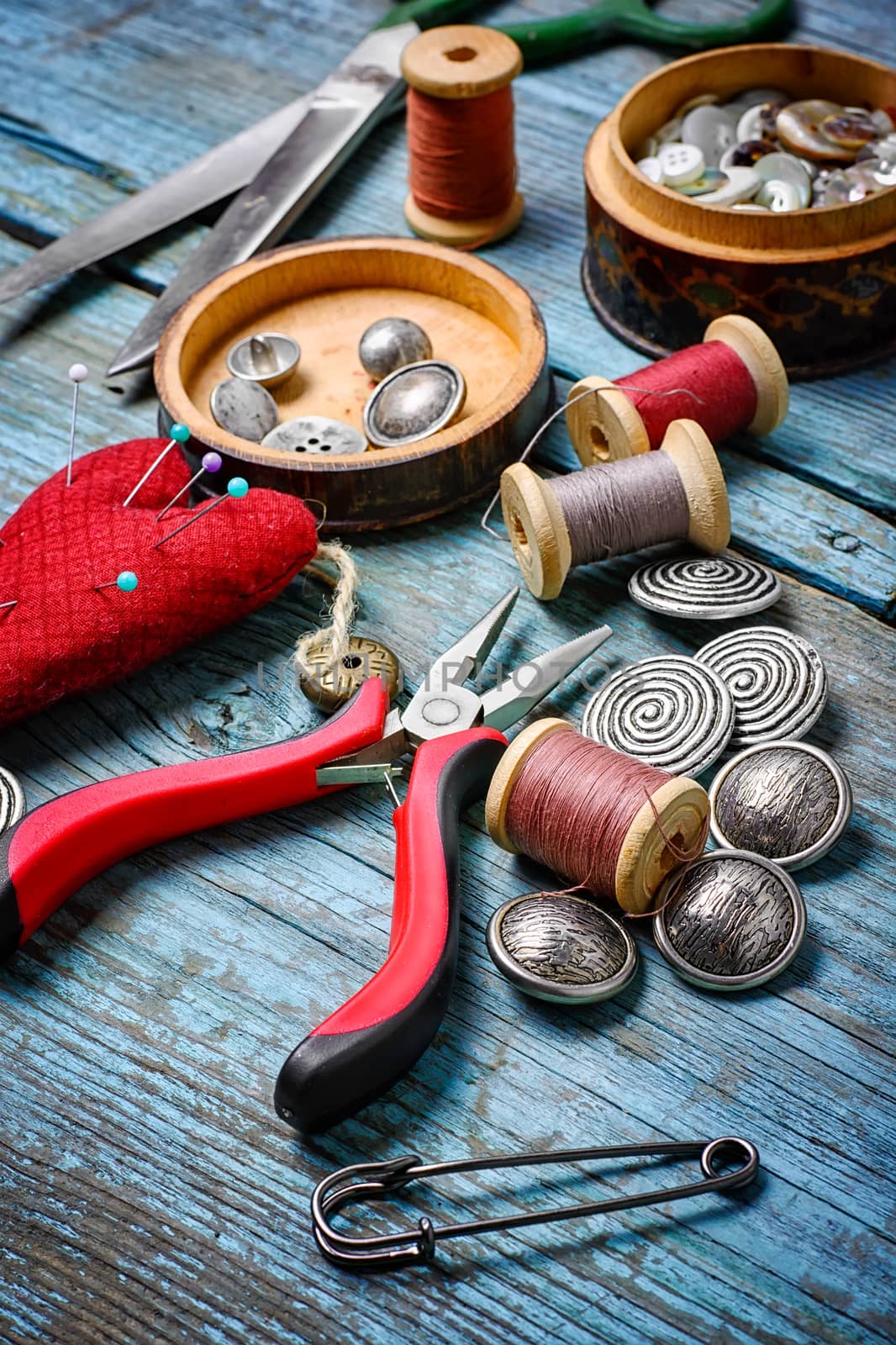 Scissors ,iron, stylish old-fashioned buttons and thread on wooden background