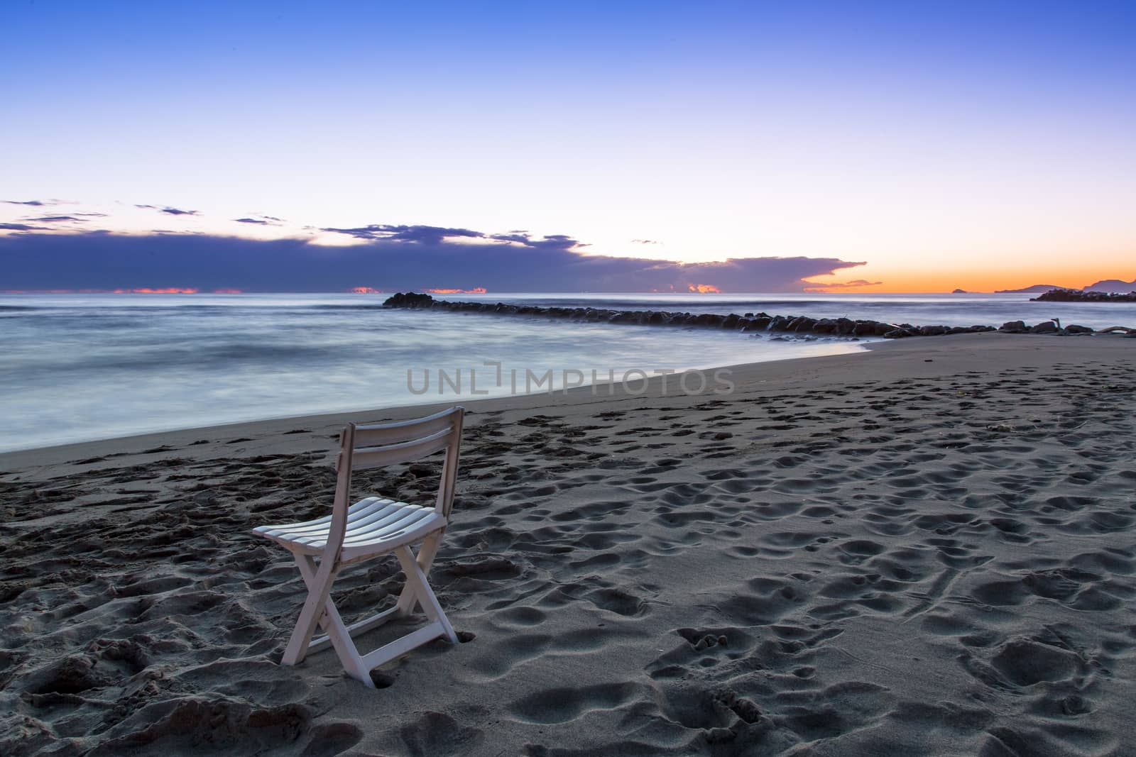 View of a chair on a beach of the Tuscan coast at sunset