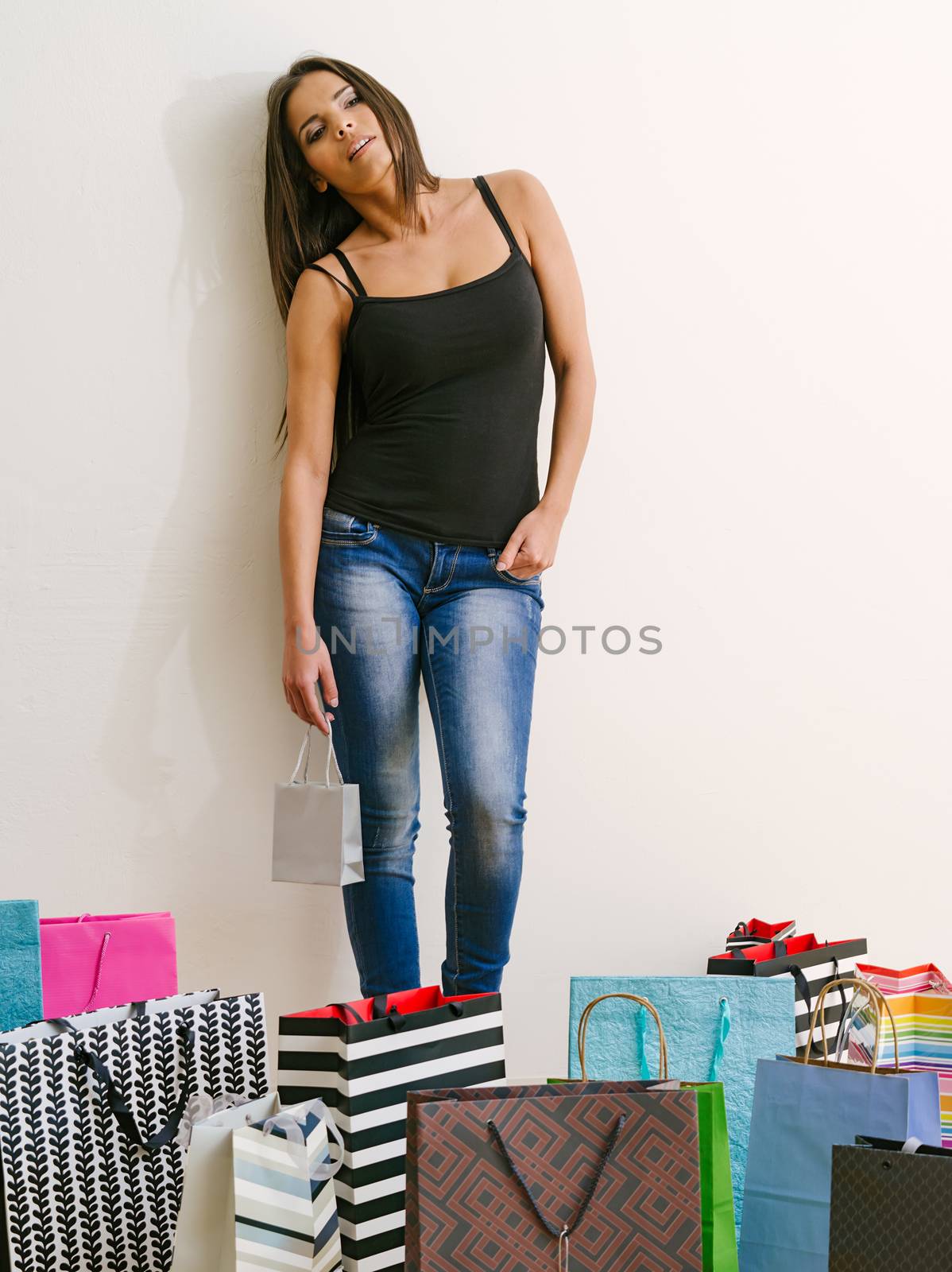 Photo of a tired young woman standing around all her shopping bags.