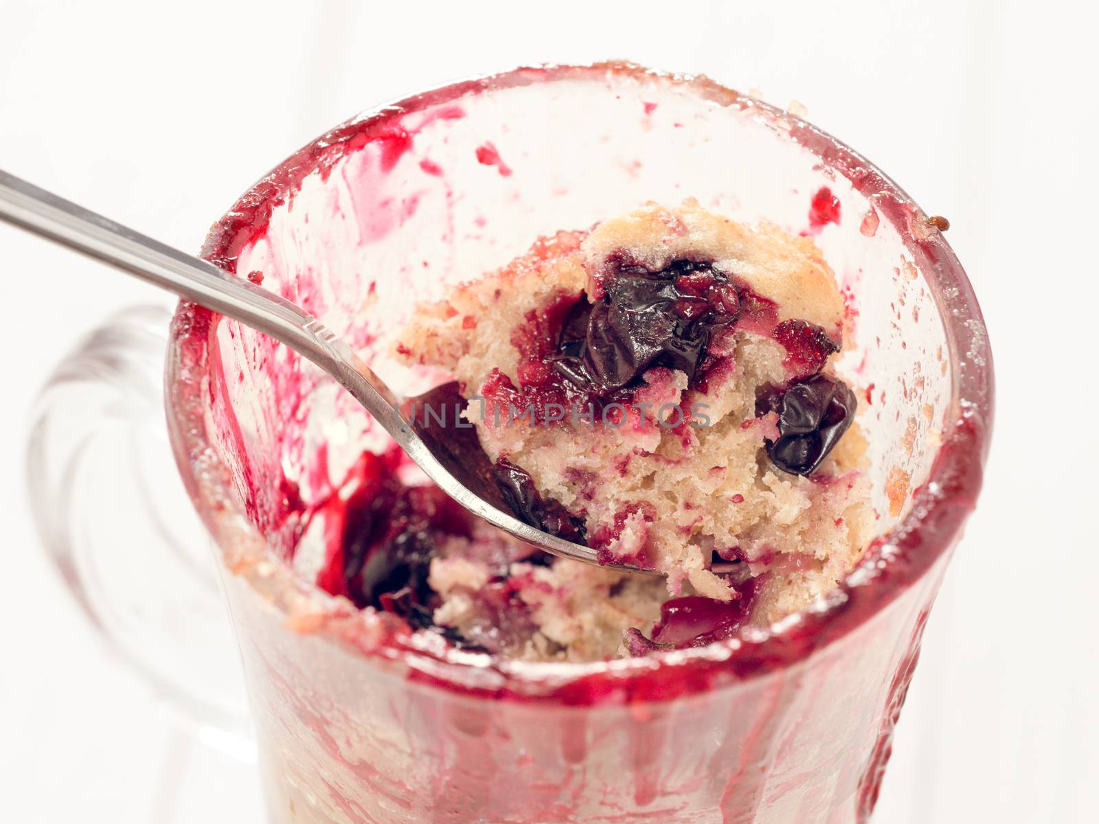 Mug Cake with berries and spoon, close up by fascinadora