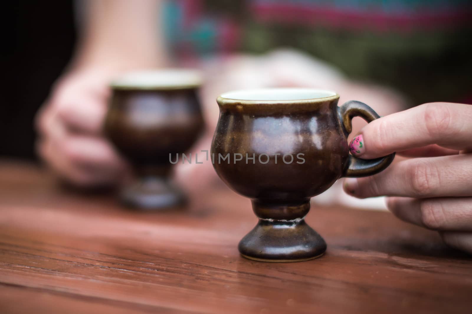 Female hands holding coffee cup over dark table by okskukuruza