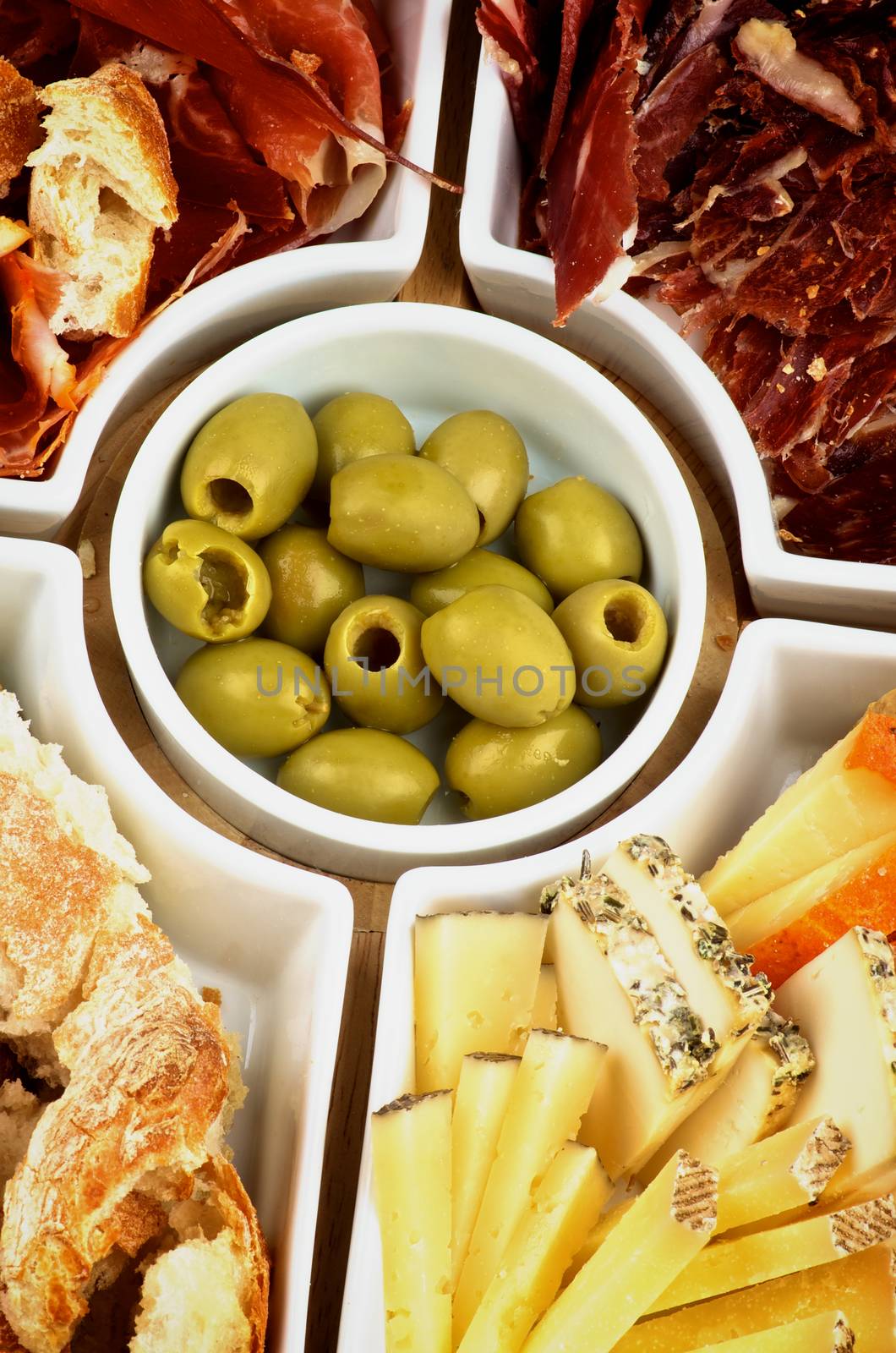 Various Spanish Snacks with Cheeses, Jamon, Cured Ham and Green Olives on Serving Plate Cross Section