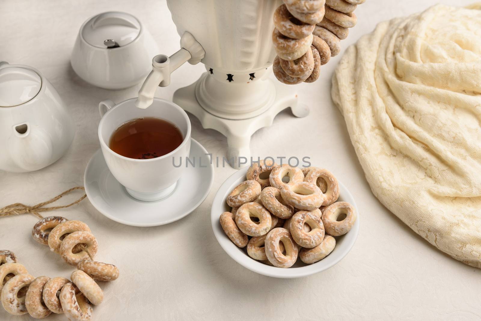 a samovar with bagels and hot tea on the white tablecloth