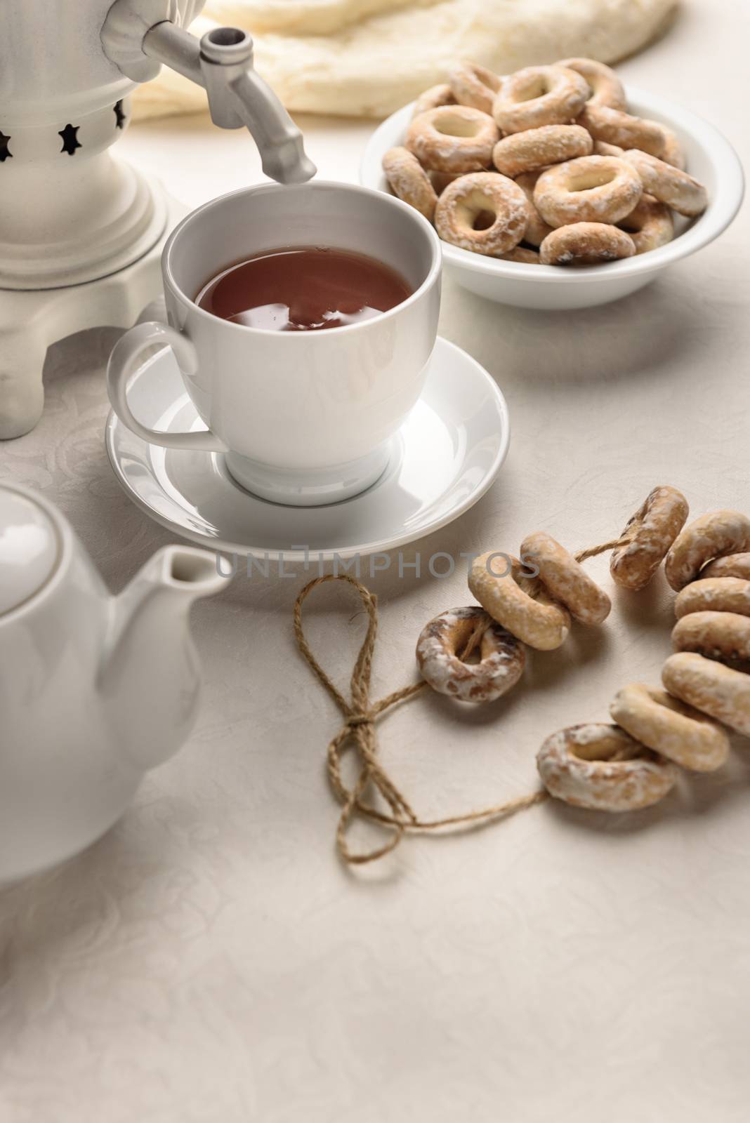 a samovar with bagels and hot tea on the white tablecloth