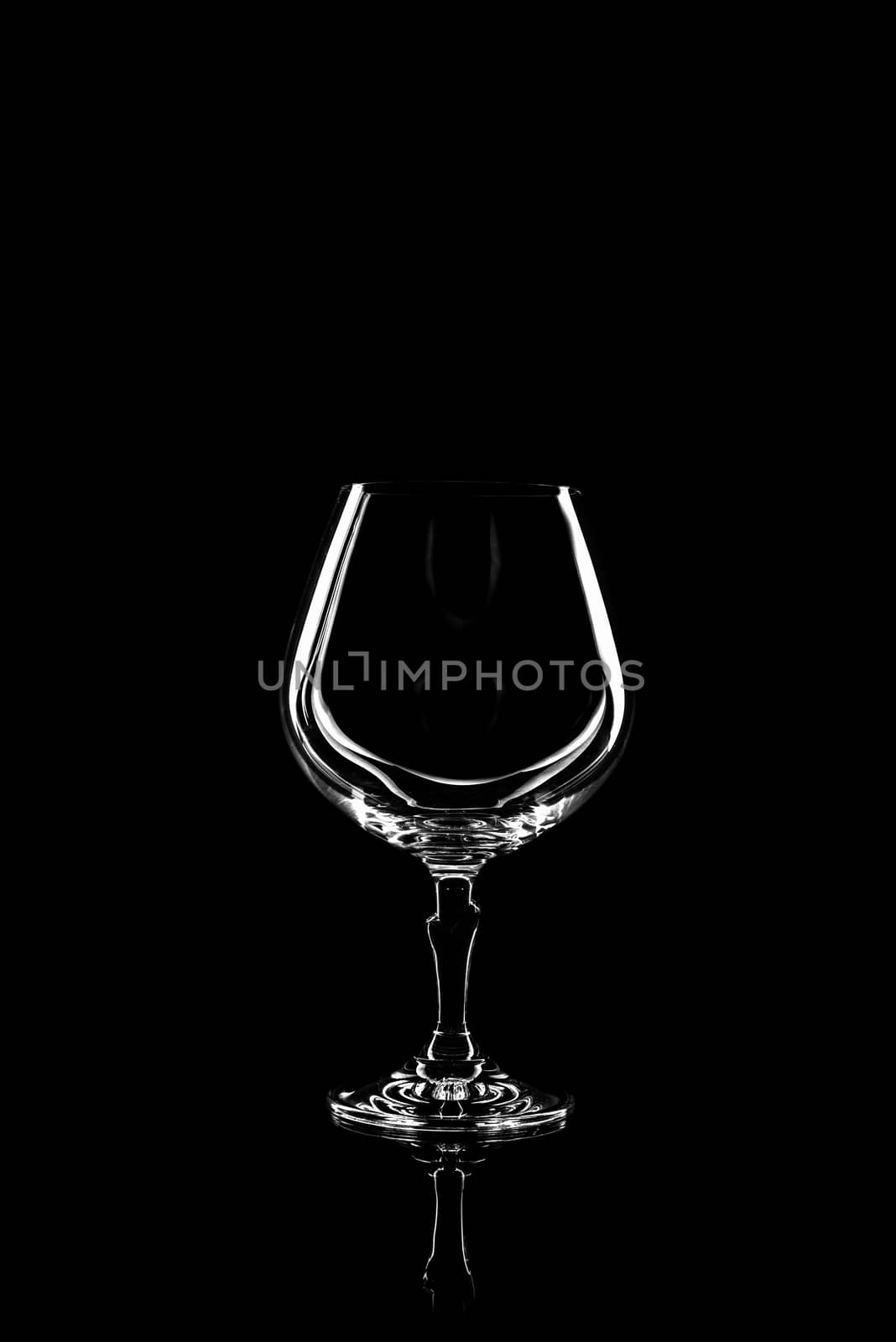 transparent glass for brandy or cognac on black background with reflection