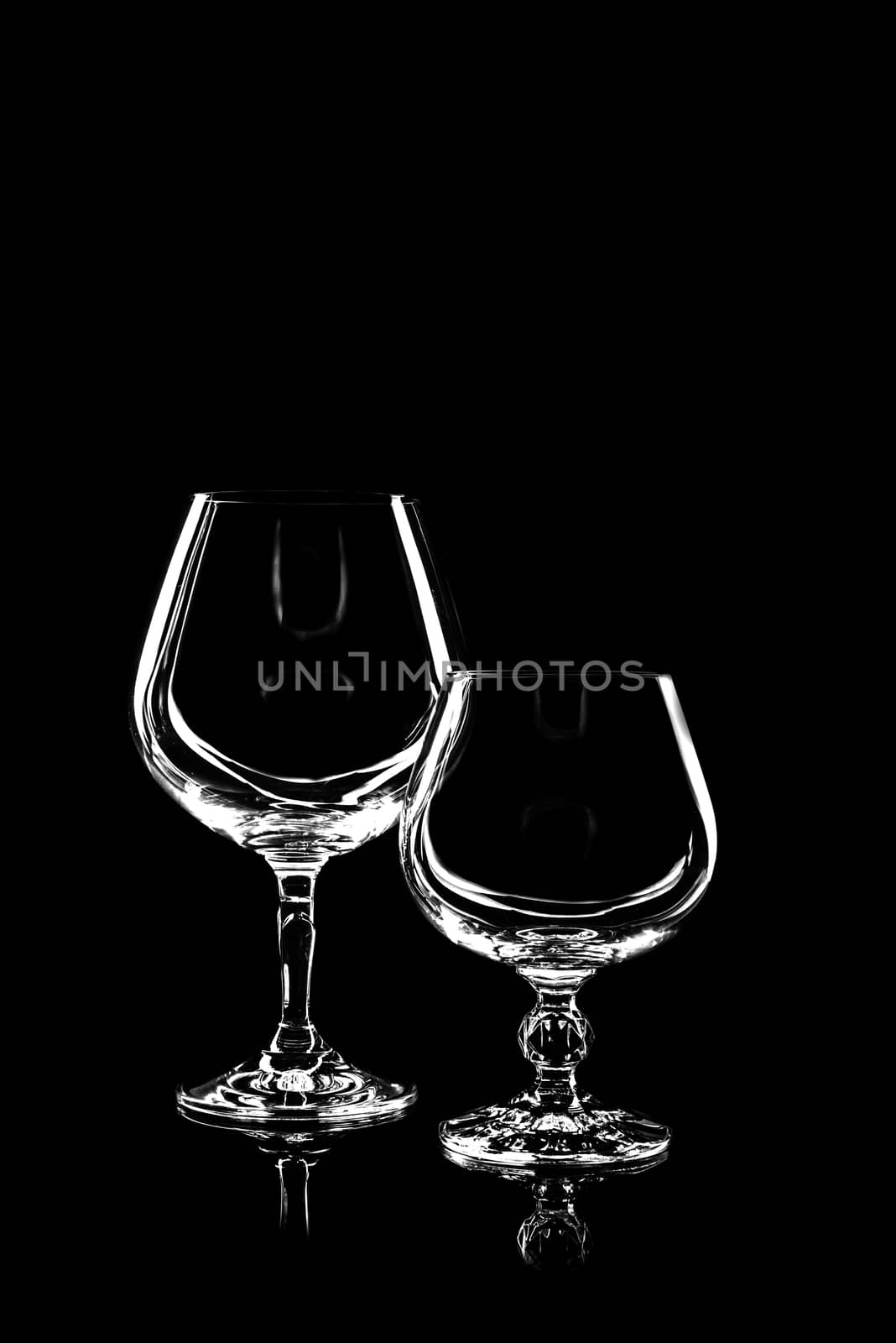 transparent glass for brandy or cognac on black background with reflection