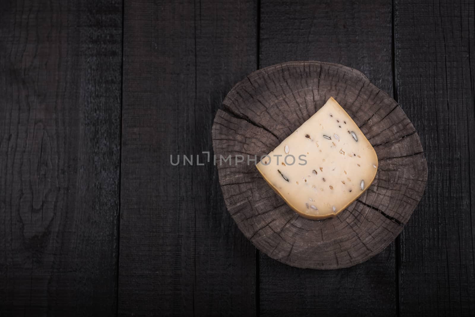 yellow cheese with seeds on a wooden end of a tree