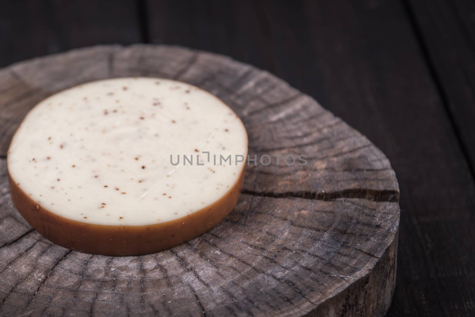 white milk cheese with seeds on a wooden end of a tree