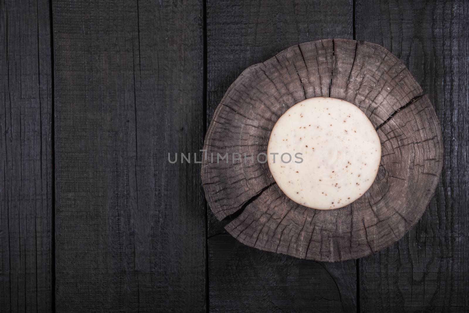 white milk cheese with seeds on a wooden end of a tree