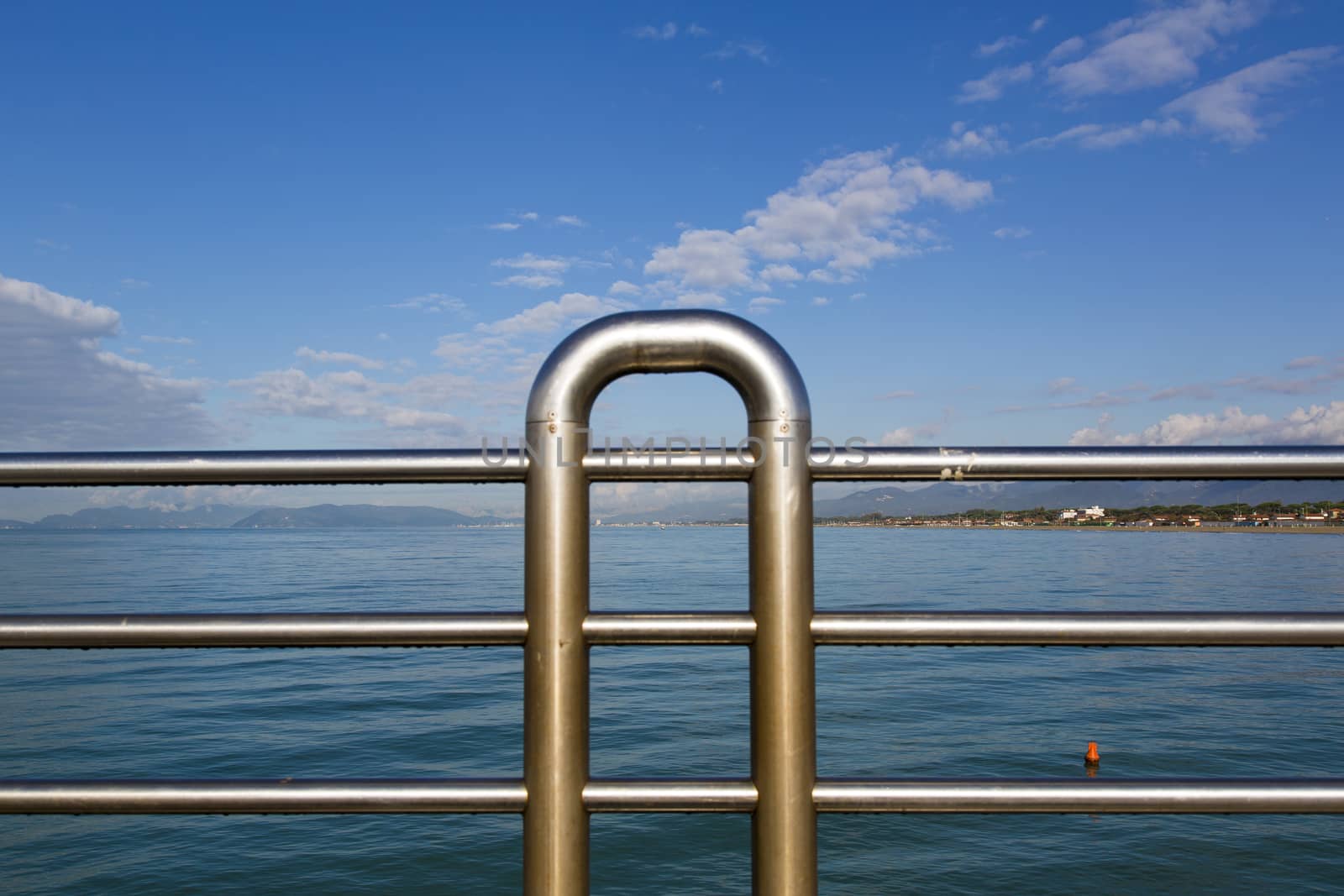 Close up view of the railing of a pier with marine landscape in the background