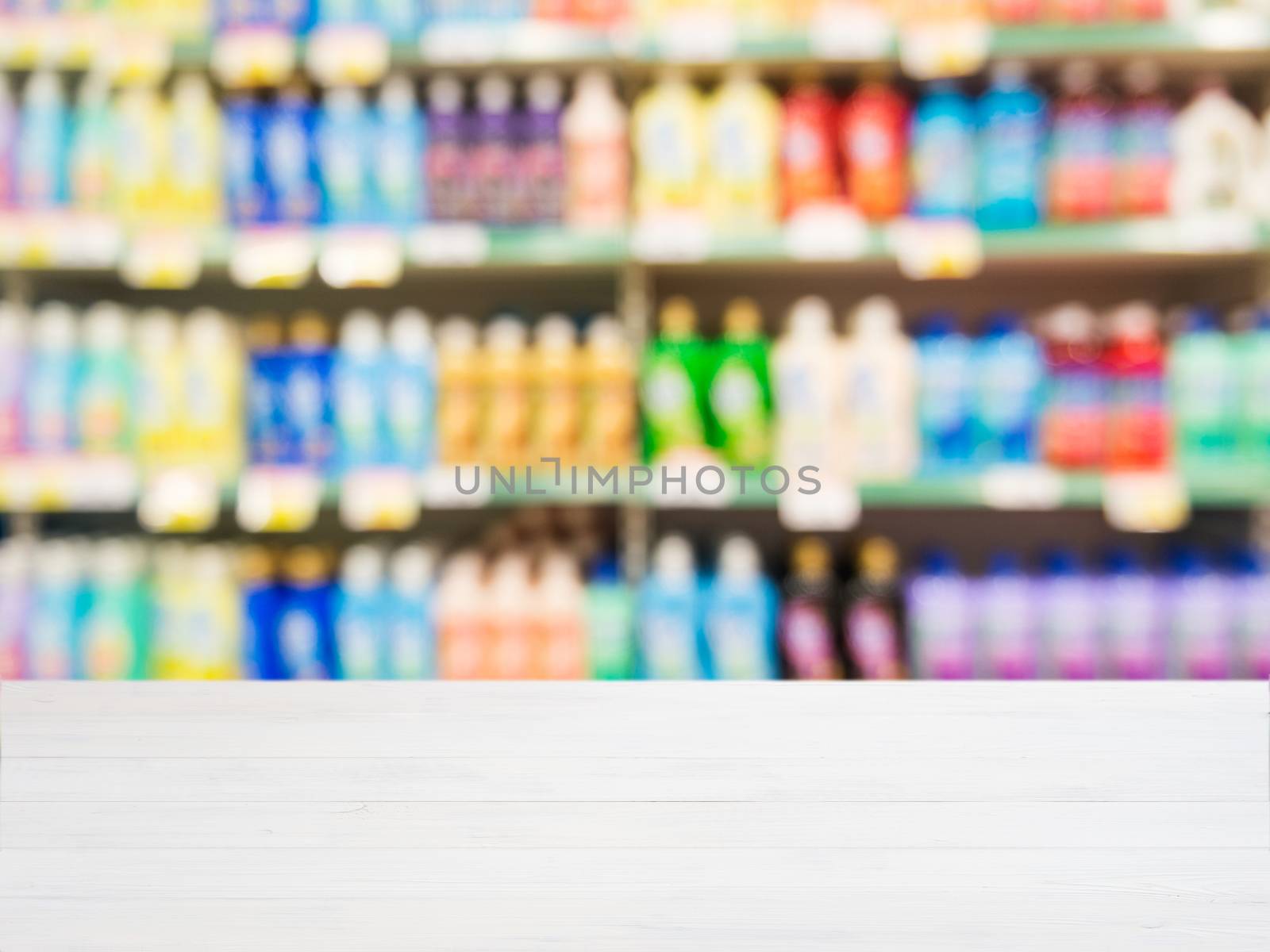 White wooden board empty table in front of blurred background. Perspective white wood board over blurred colorful supermarket products on shelvest - mockup for display of product