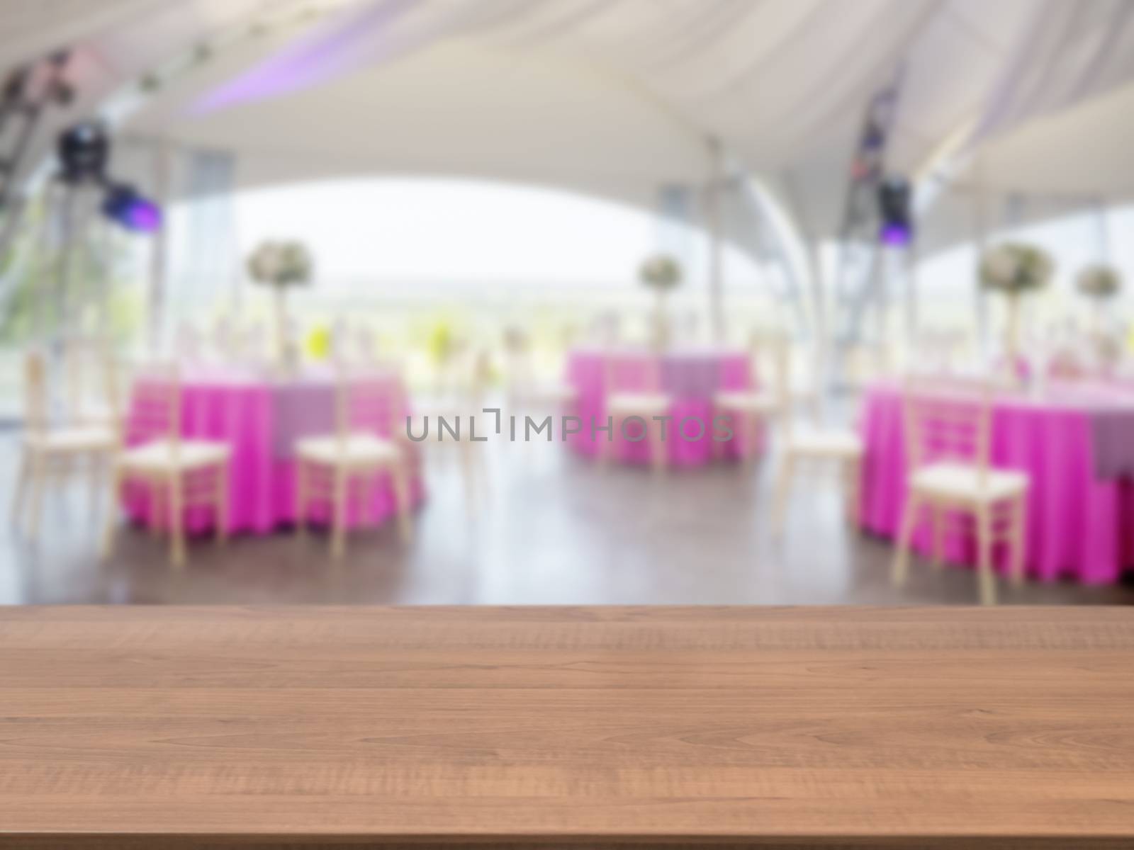 Dark wooden empty table in front of blurred restaurant interior background. Perspective brown wood board over blur in restaurant or cafe - mockup for display or montage your products