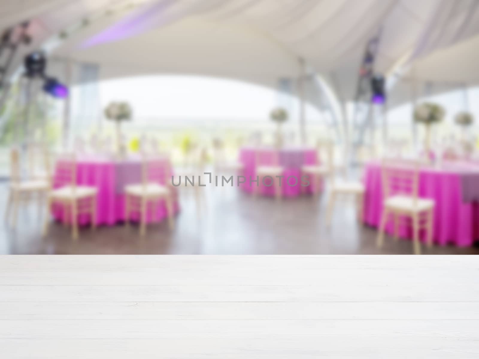 White wooden empty table in front of blurred restaurant interior background. Perspective white wood board over blur in restaurant or cafe - mockup for display or montage your products