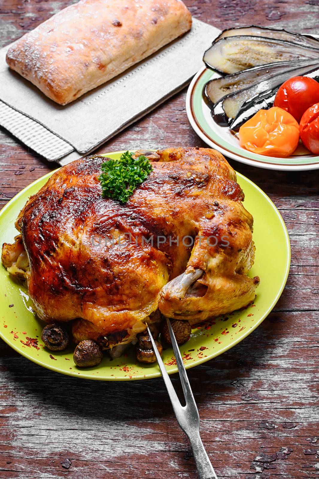 Whole roasted chicken with baked vegetables on wooden background