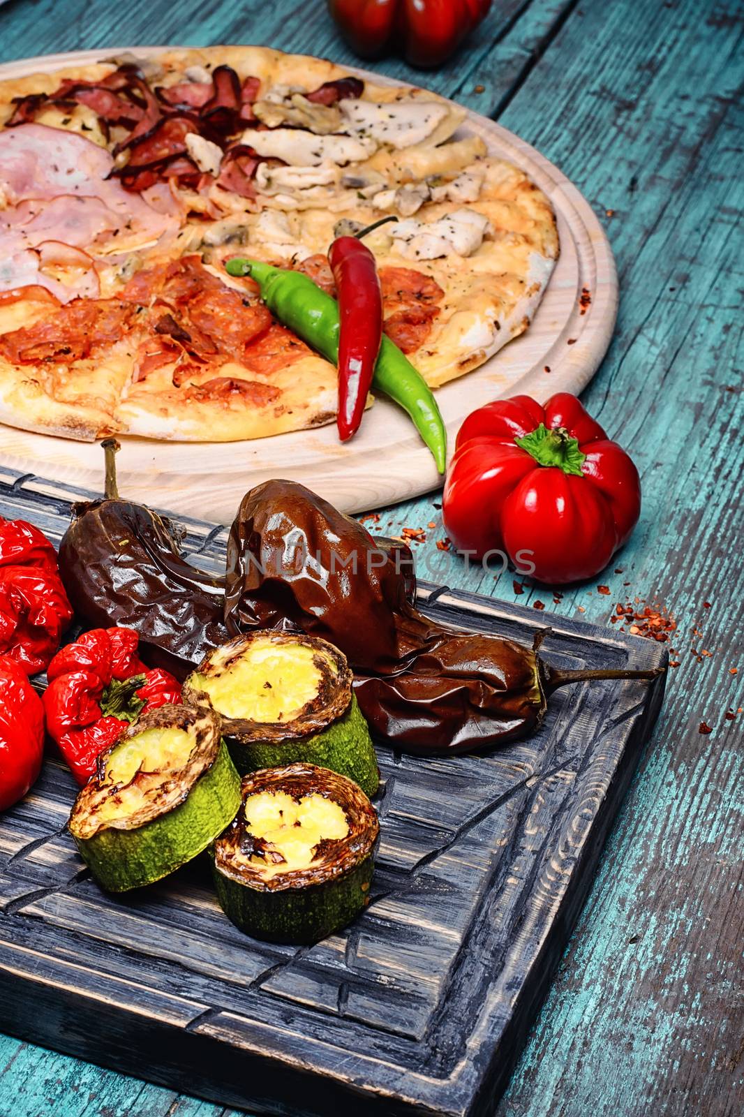 Italian pizza with meat and baked vegetables on the kitchen board