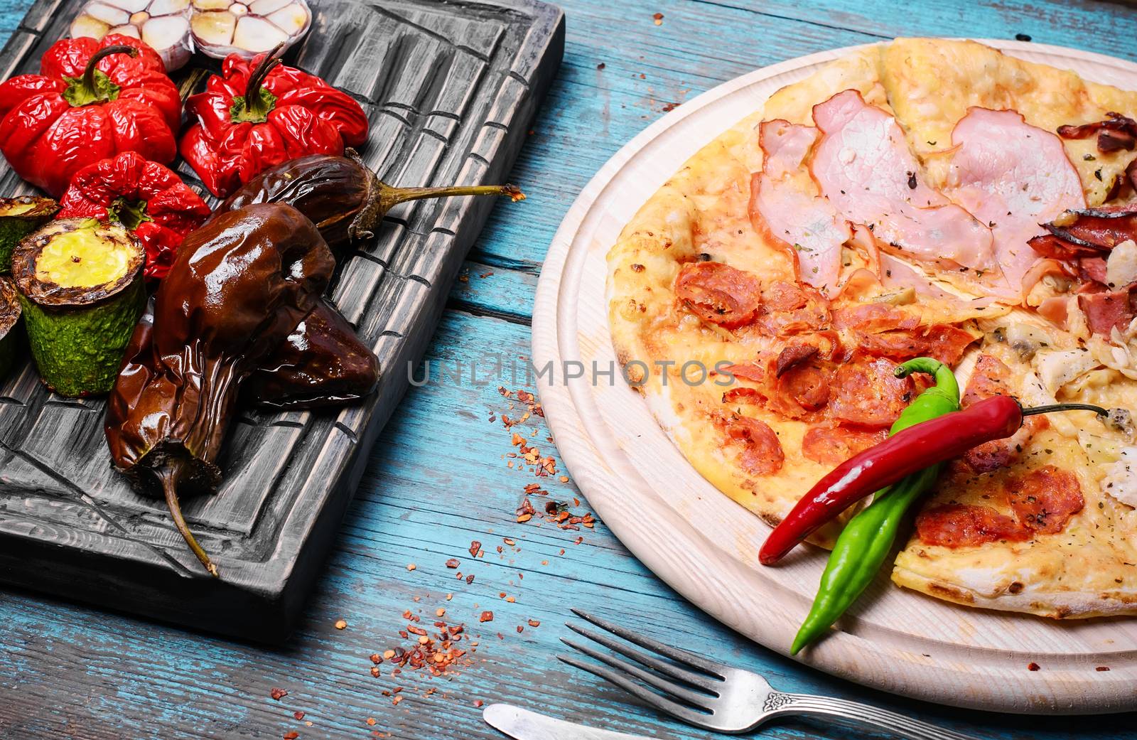 Italian pizza with meat and baked vegetables on the kitchen board