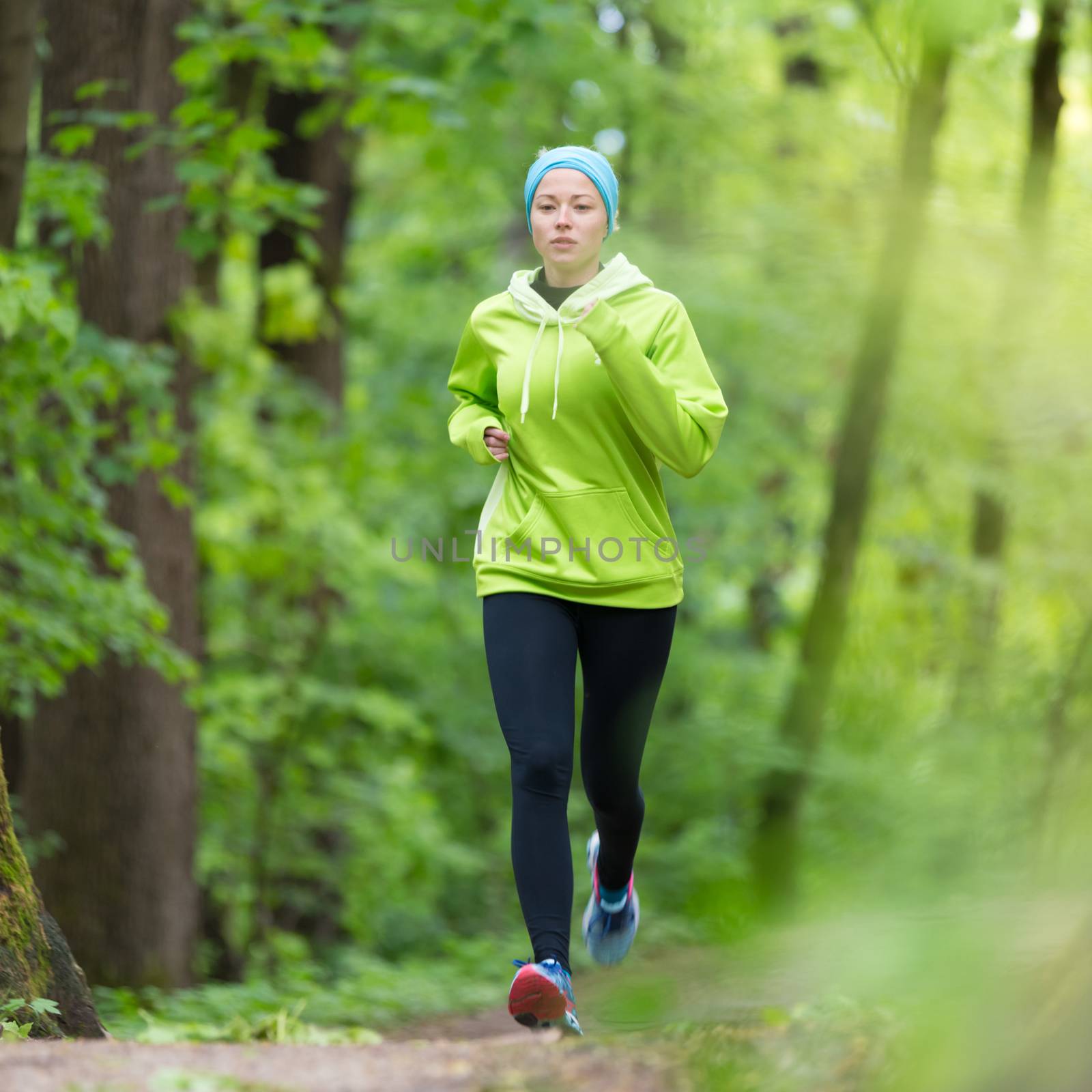 Sporty young female runner in the forest.  by kasto