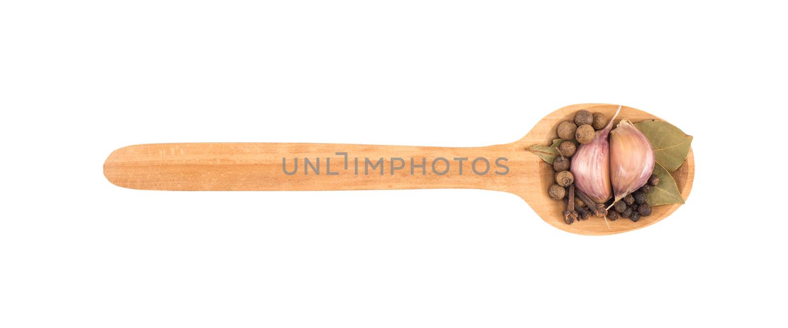 Garlic in a wooden spoon with bay leaf herb and black peppercorns isolated over white background.