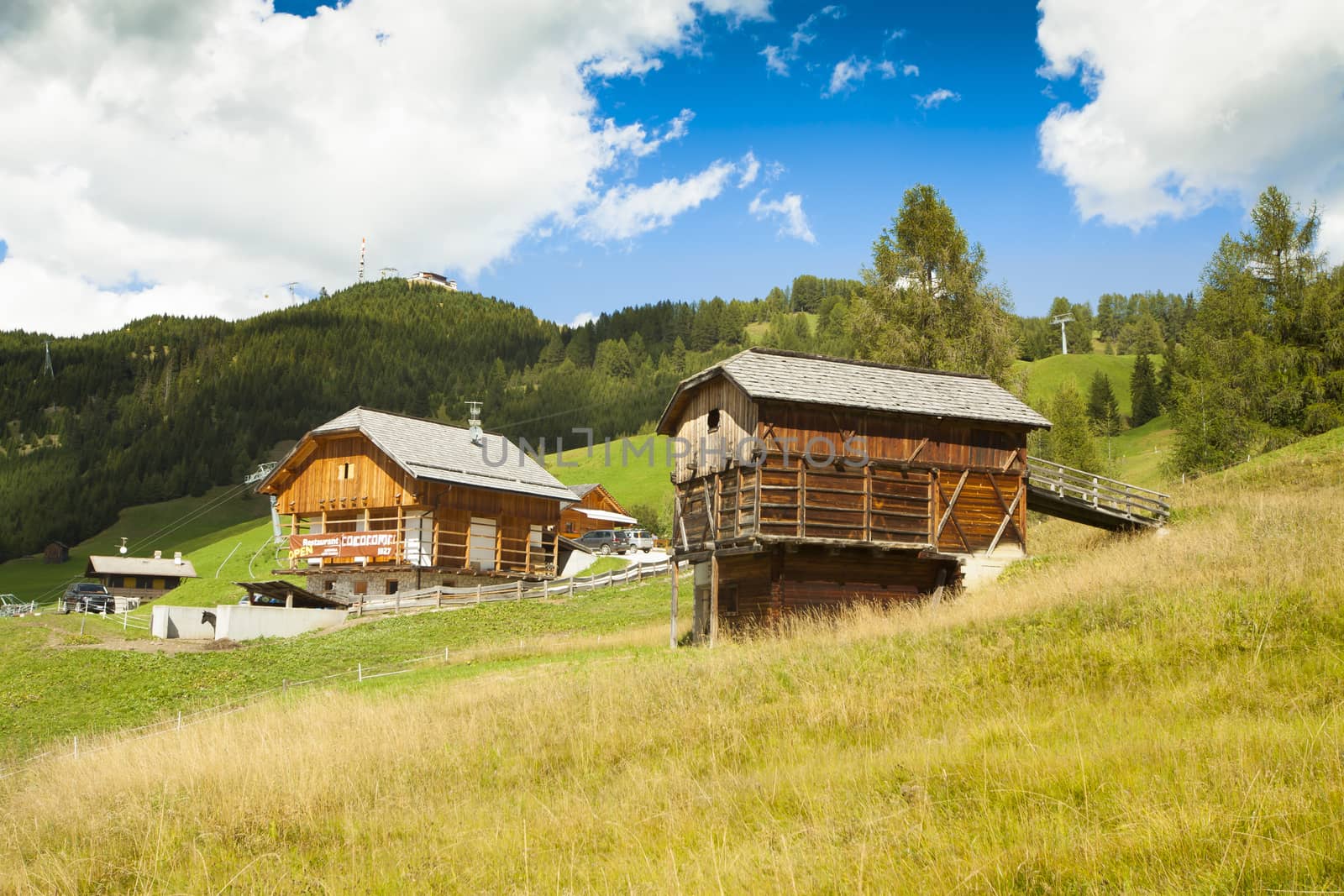 A refuge and a restaurant in nearby high Badia on green grass with blue sky and white clouds