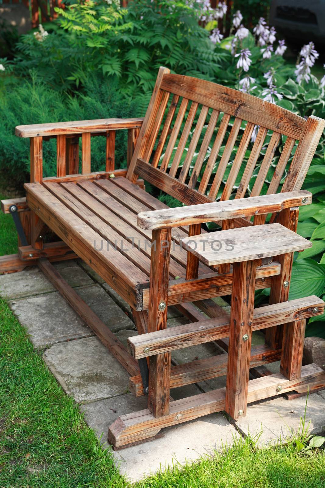 Old wooden bench in garden on background with plants