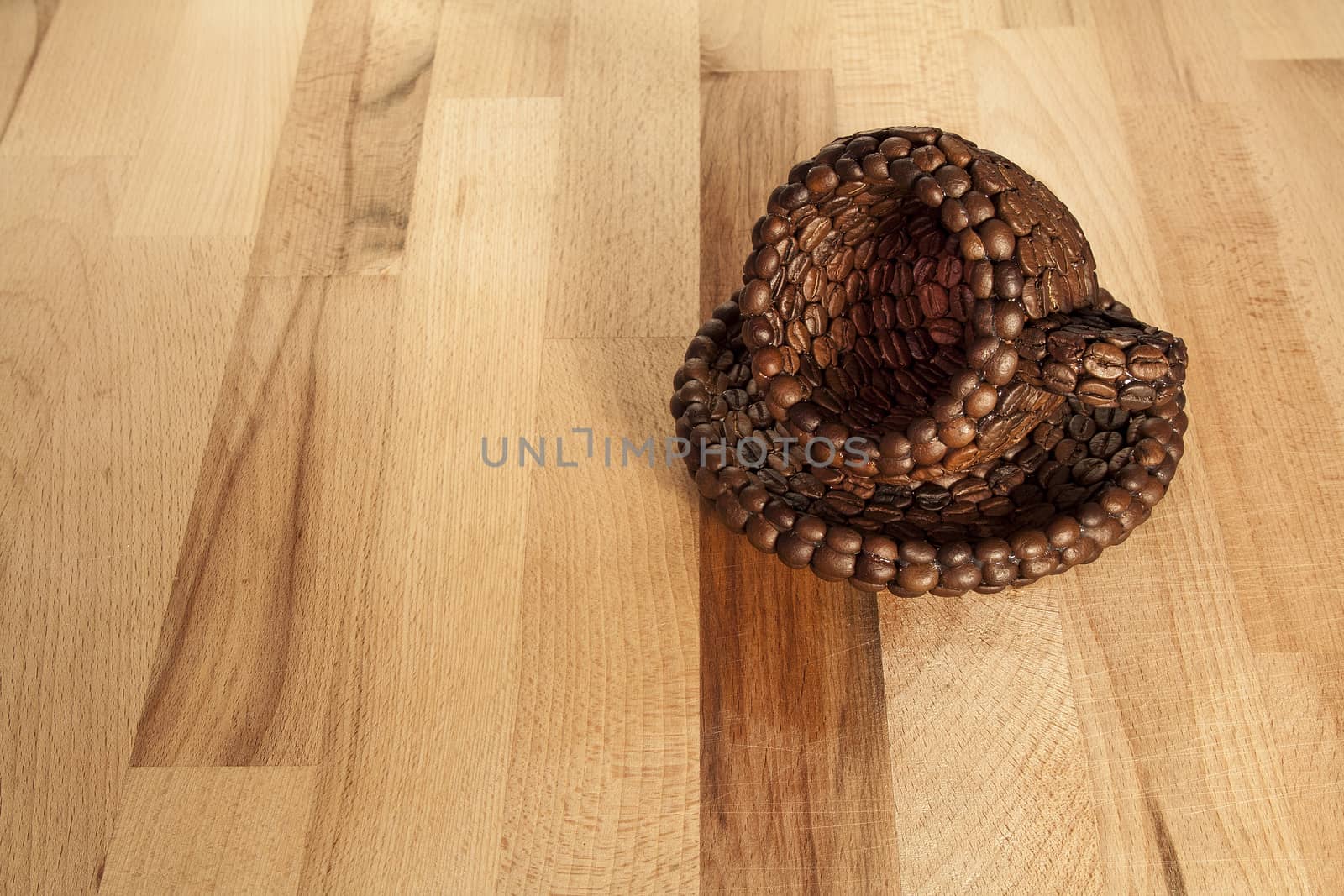 Close up view of a cup covered with coffee beans on a wooden surface