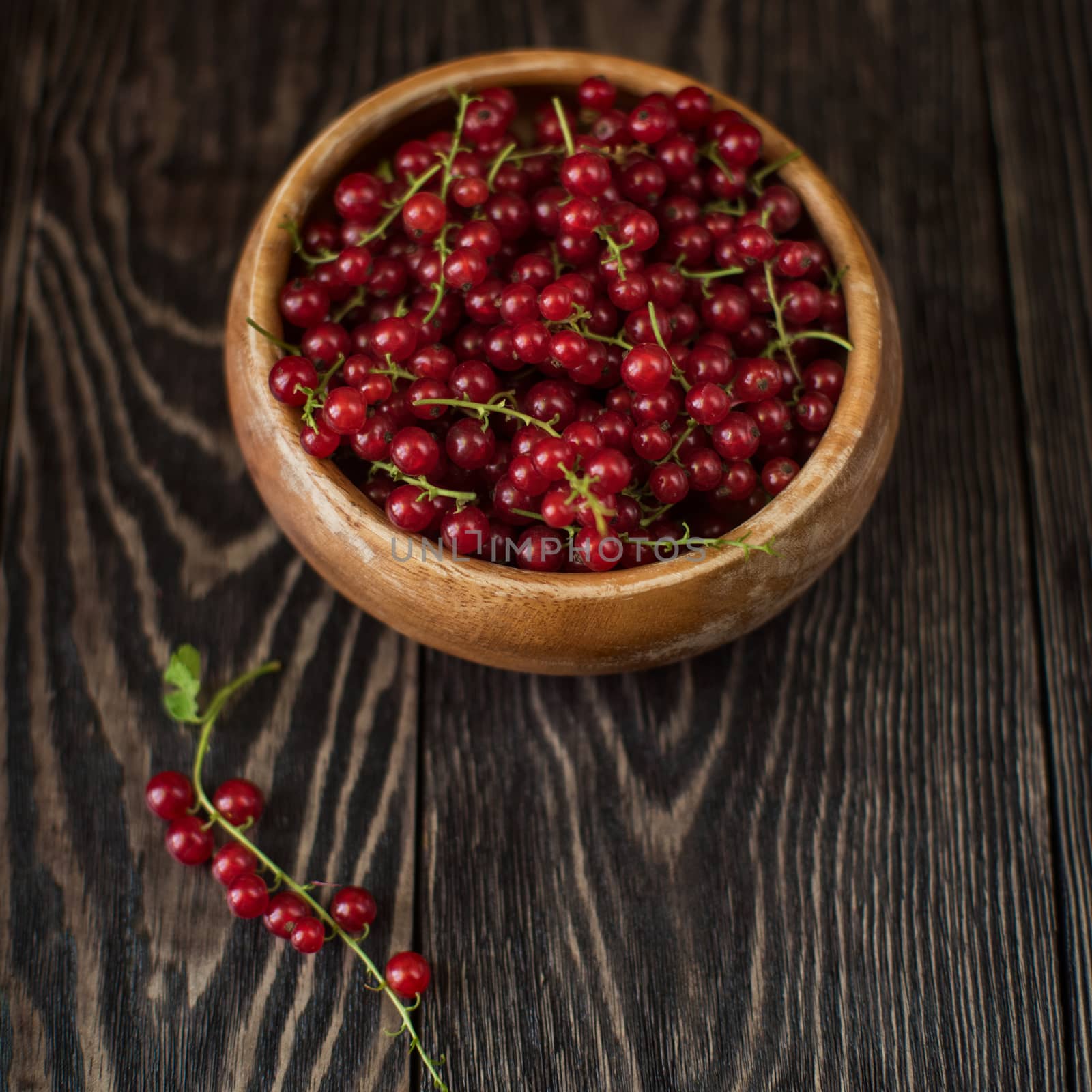 Fresh red currants in plate on wooden table