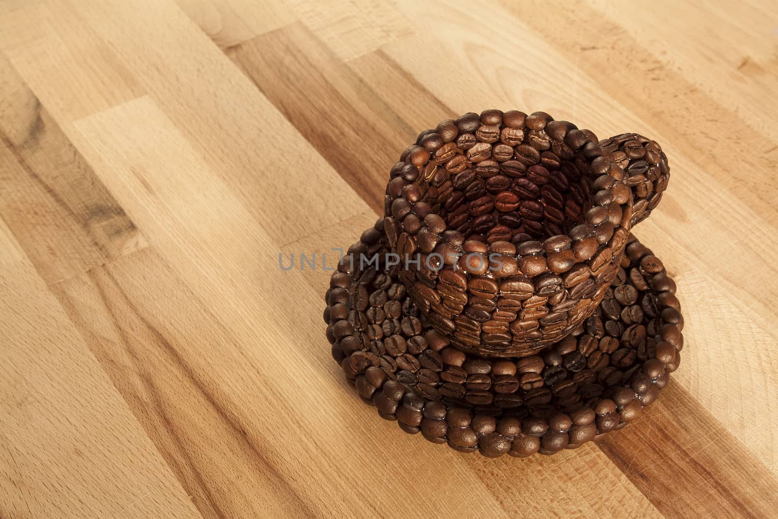 Close up view of a cup covered with coffee beans on a wooden surface