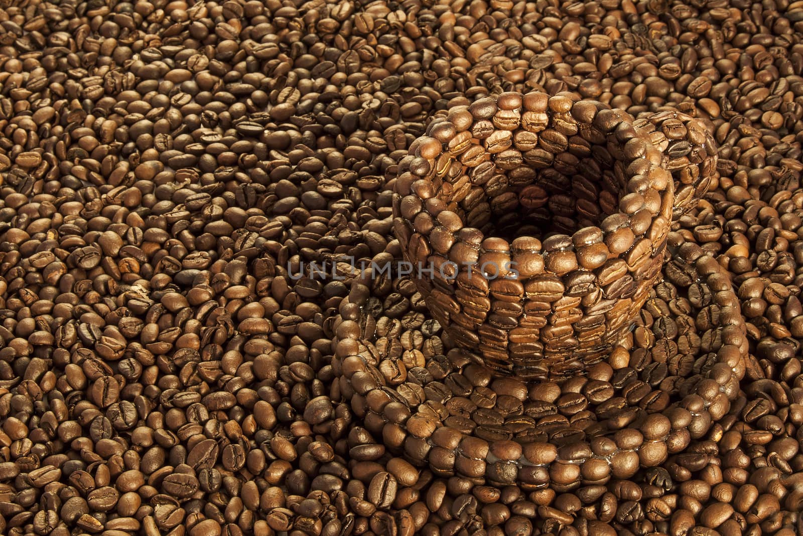 Close up view of a cup covered with coffee beans above a floor covered with coffee beans