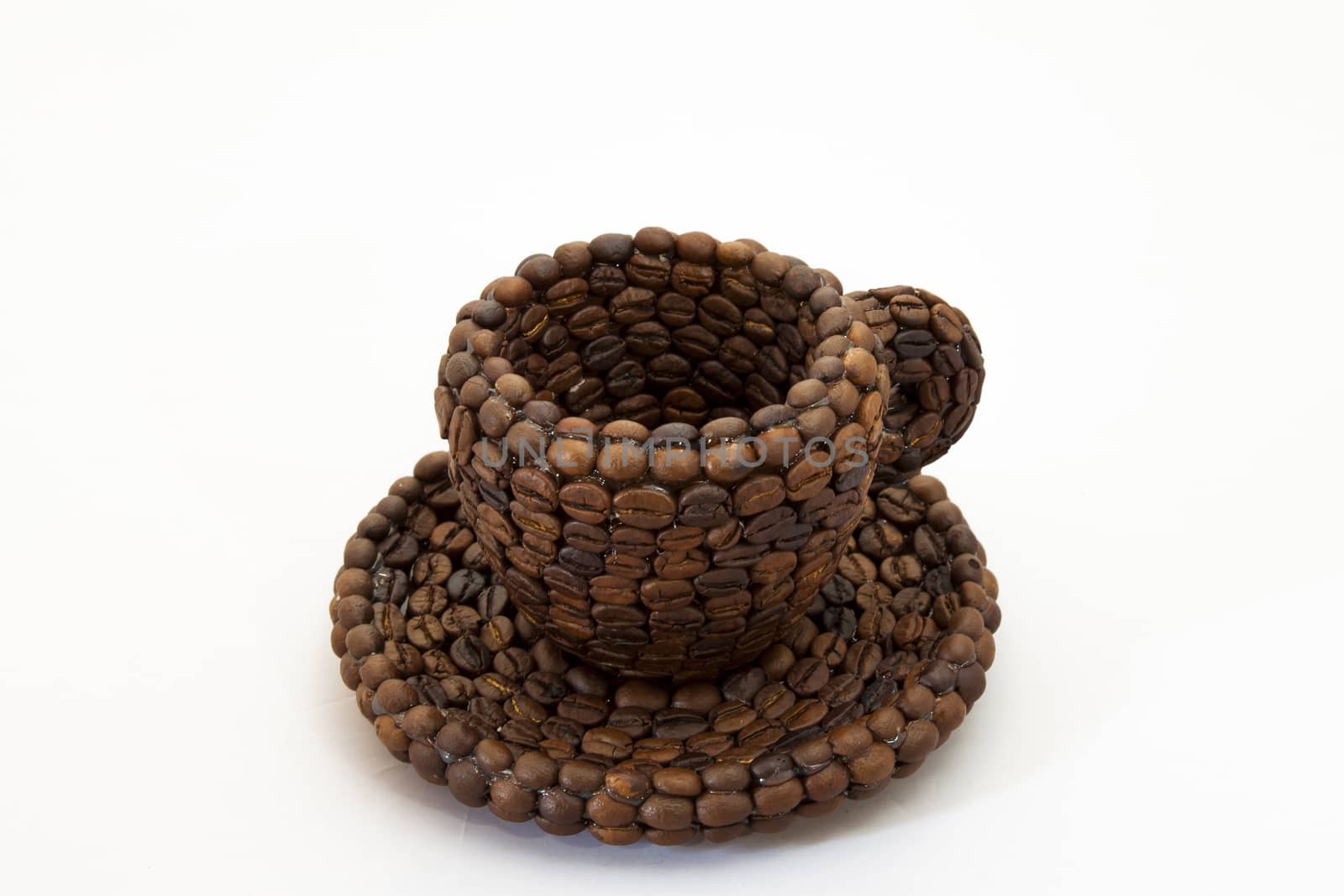 Close up view of a cup covered with coffee beans and white background