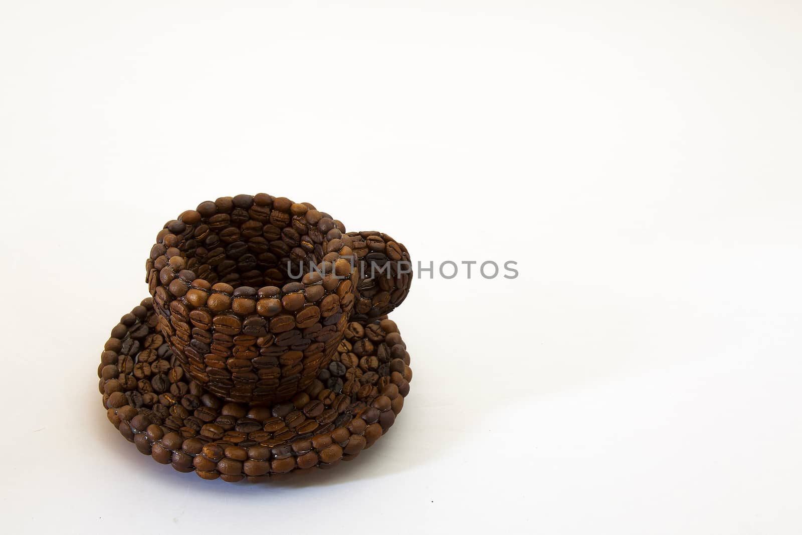 Close up view of a cup covered with coffee beans and white background