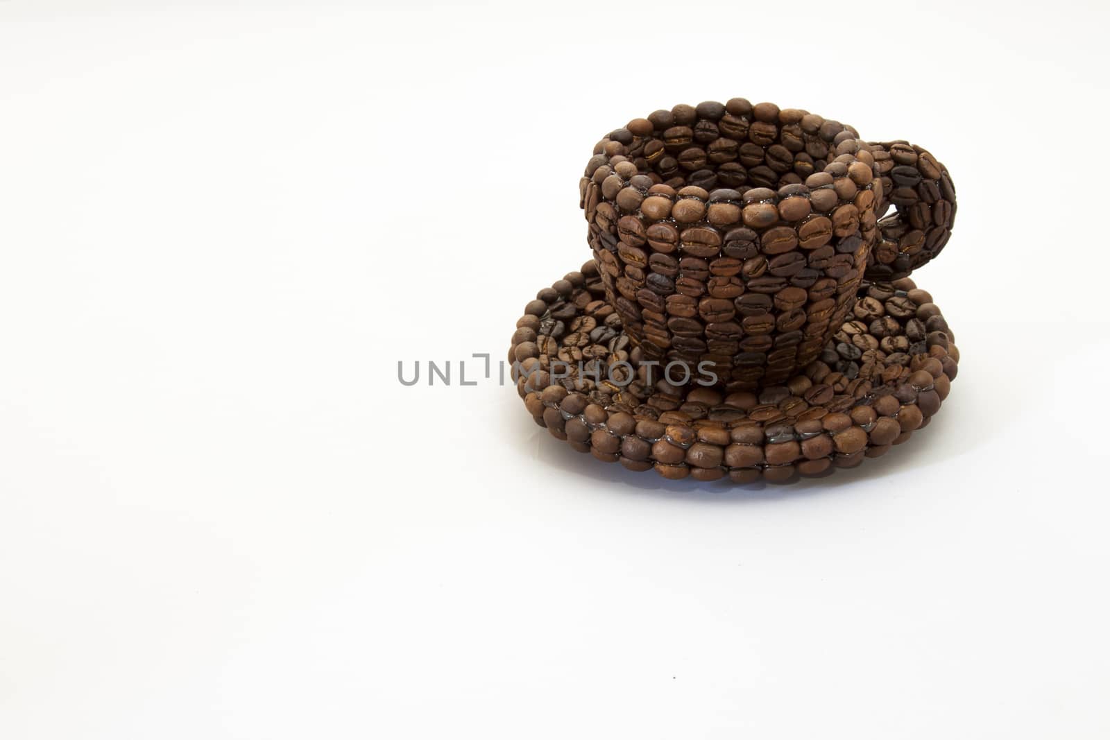 Close up view of a cup covered with coffee beans and white background