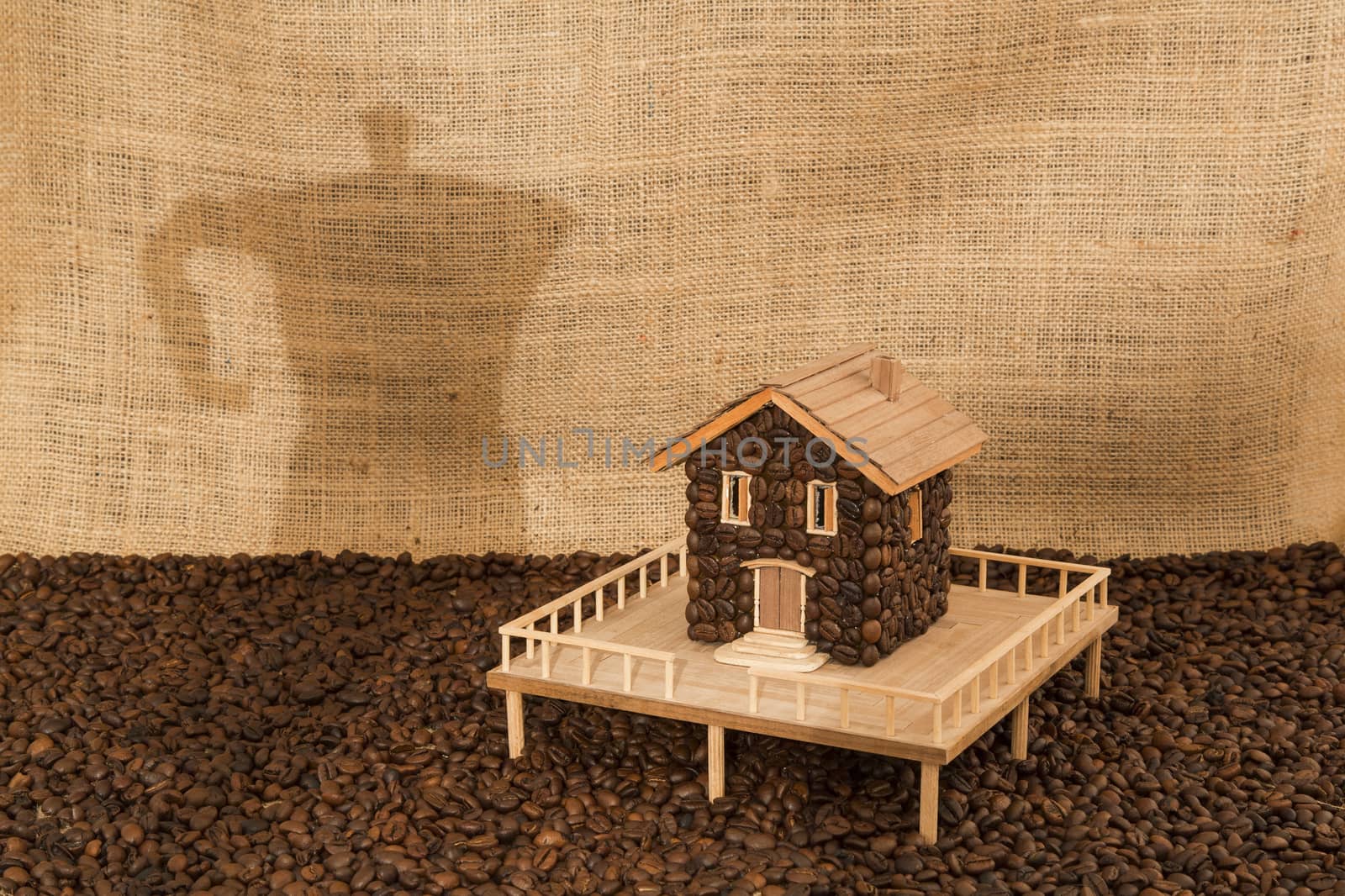House made of coffee on sea of coffee and background screening shadow of a coffee machine