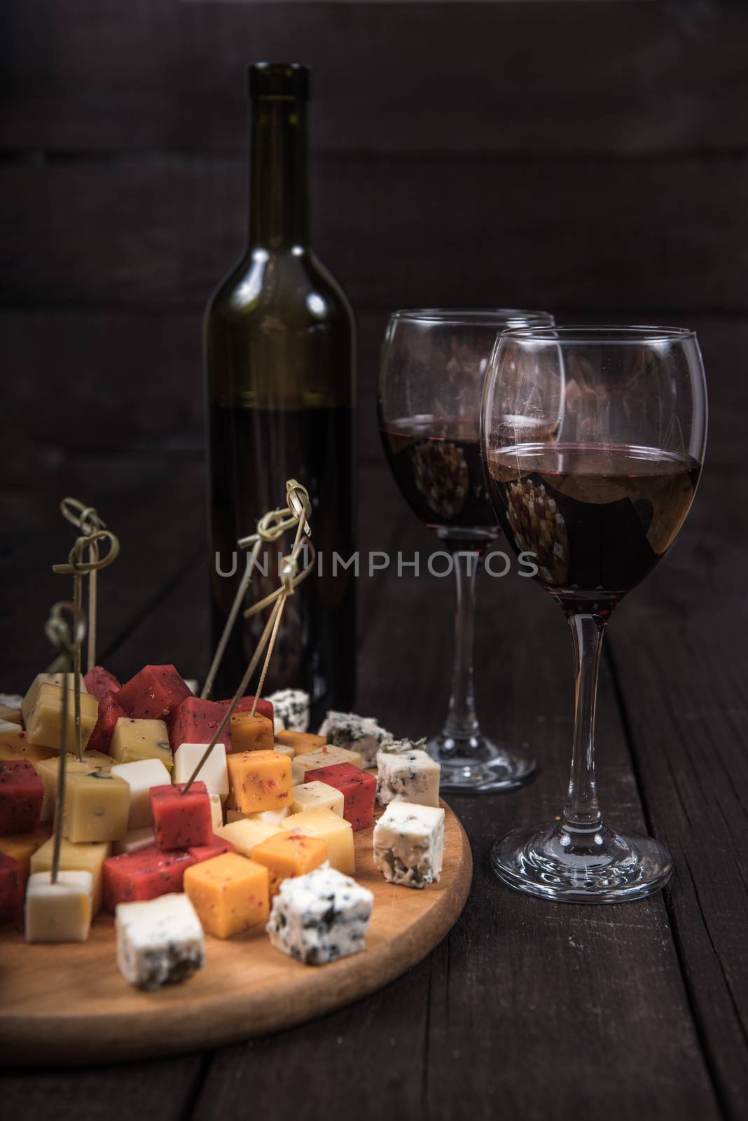 many kinds of cheeses on wooden end of a tree with reed wine