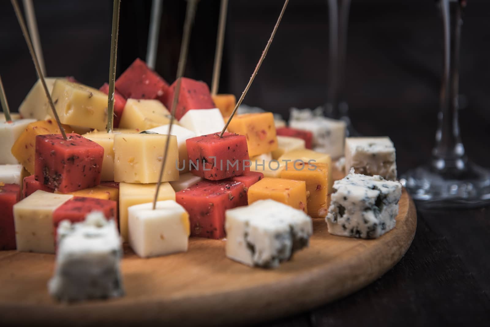 many kinds of cheeses on wooden end of a tree with reed wine