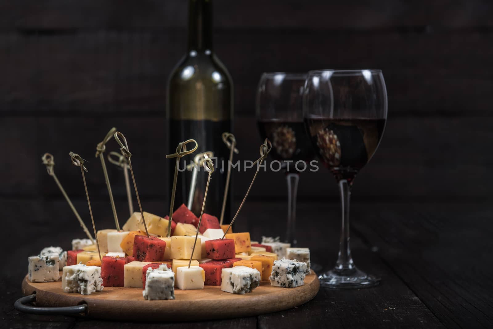 many kinds of cheeses on wooden end of a tree with reed wine