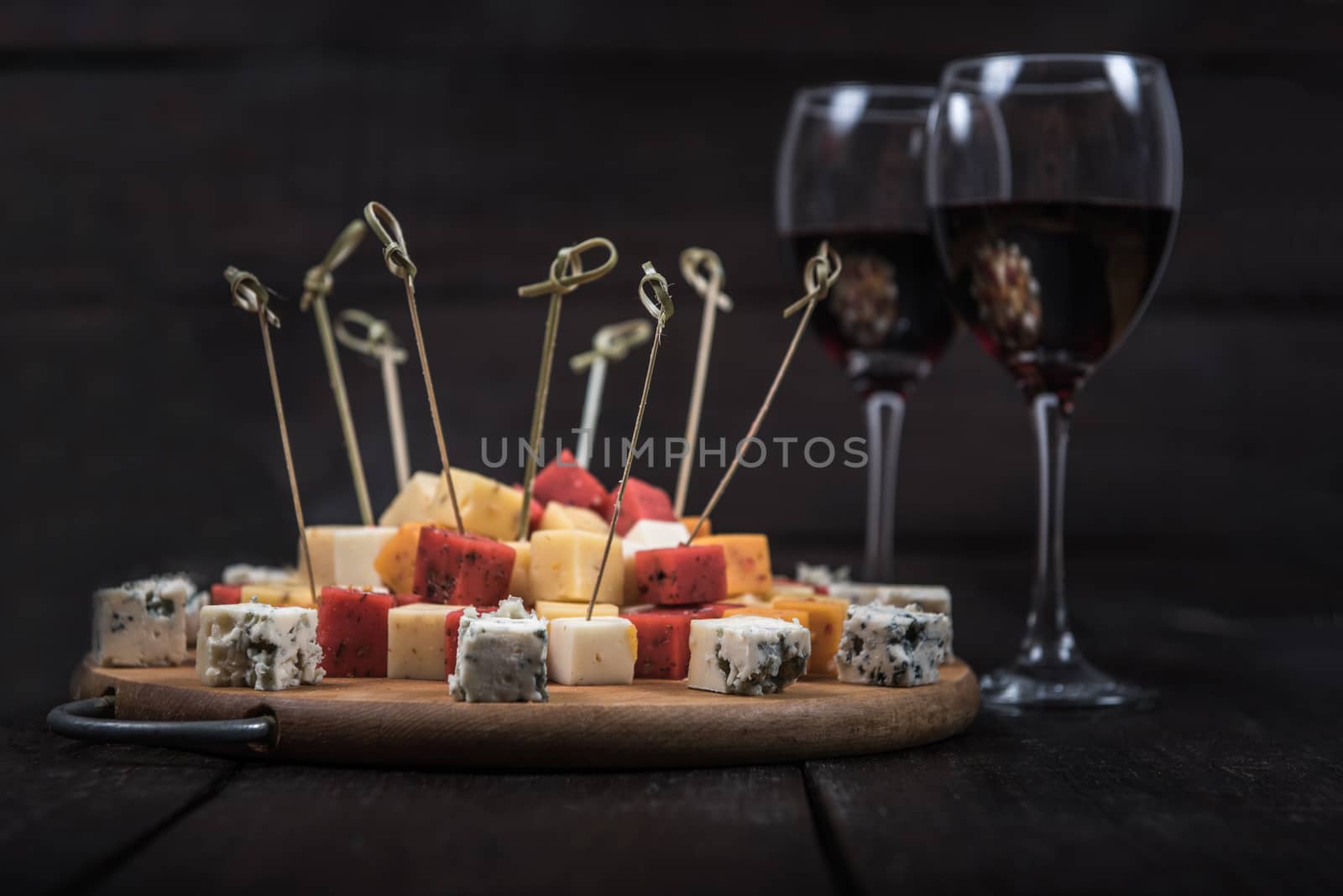 many kinds of cheeses on wooden end of a tree with reed wine