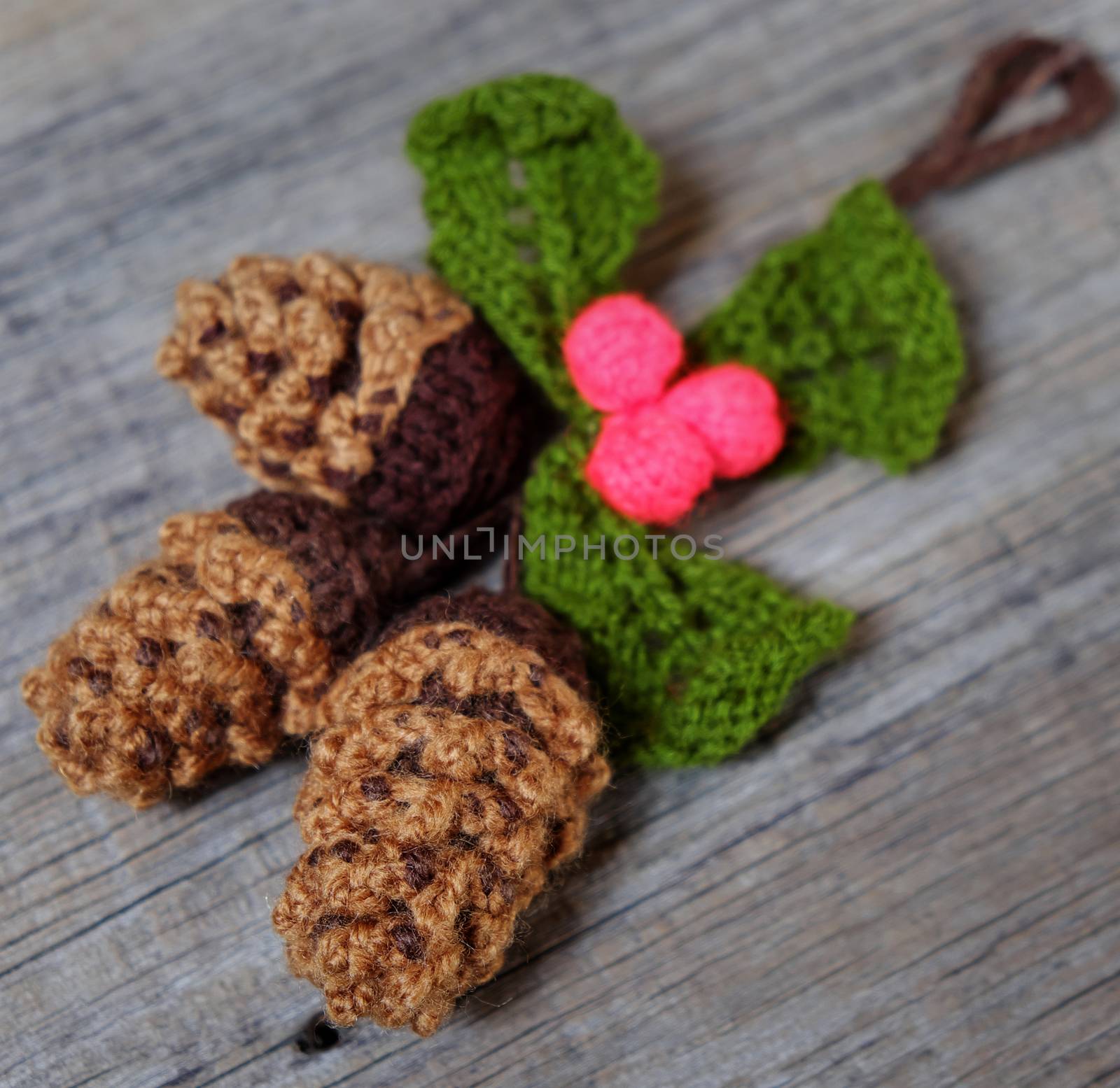 Nice handmade ornament for winter holiday, group of knitted pinecone, holly leaf, berries knit from yarn, message Merry Christmas on tag, nice Xmas background