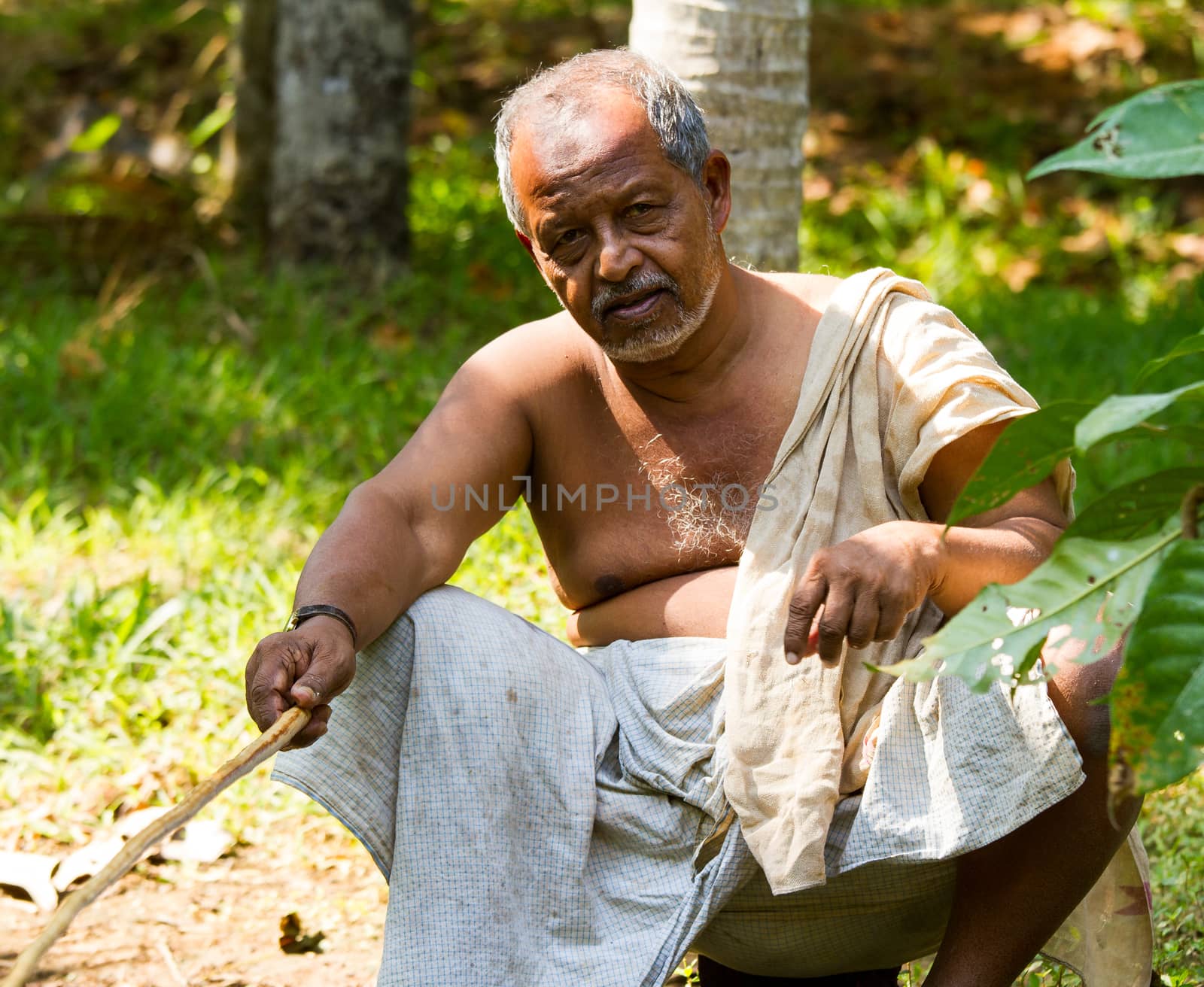Tanned old Indian fishing with home-made fishing rod at the hot sunny day in Kerala backwaters by straannick