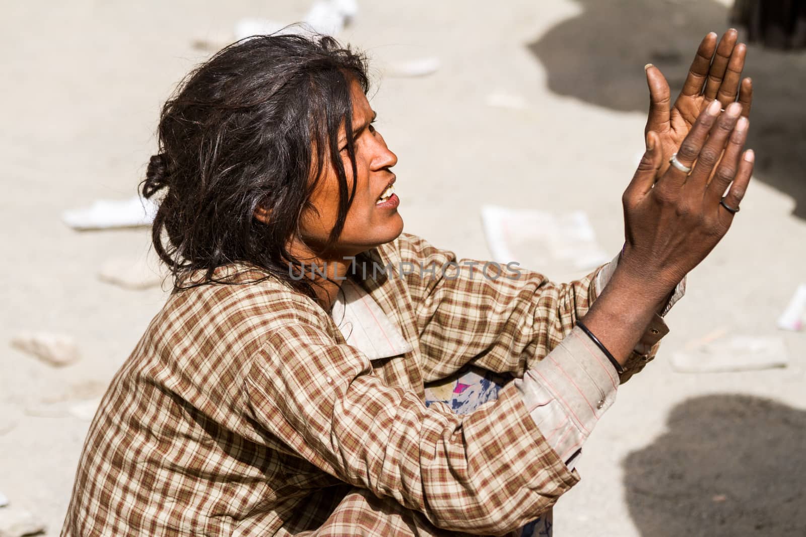 Hemis, India - June 29, 2012:  homeless beggar women with outstretched arms asking for alms from visitors of the Cham Dance Festival of Tibetan buddhism in Hemis monastery, India. by straannick